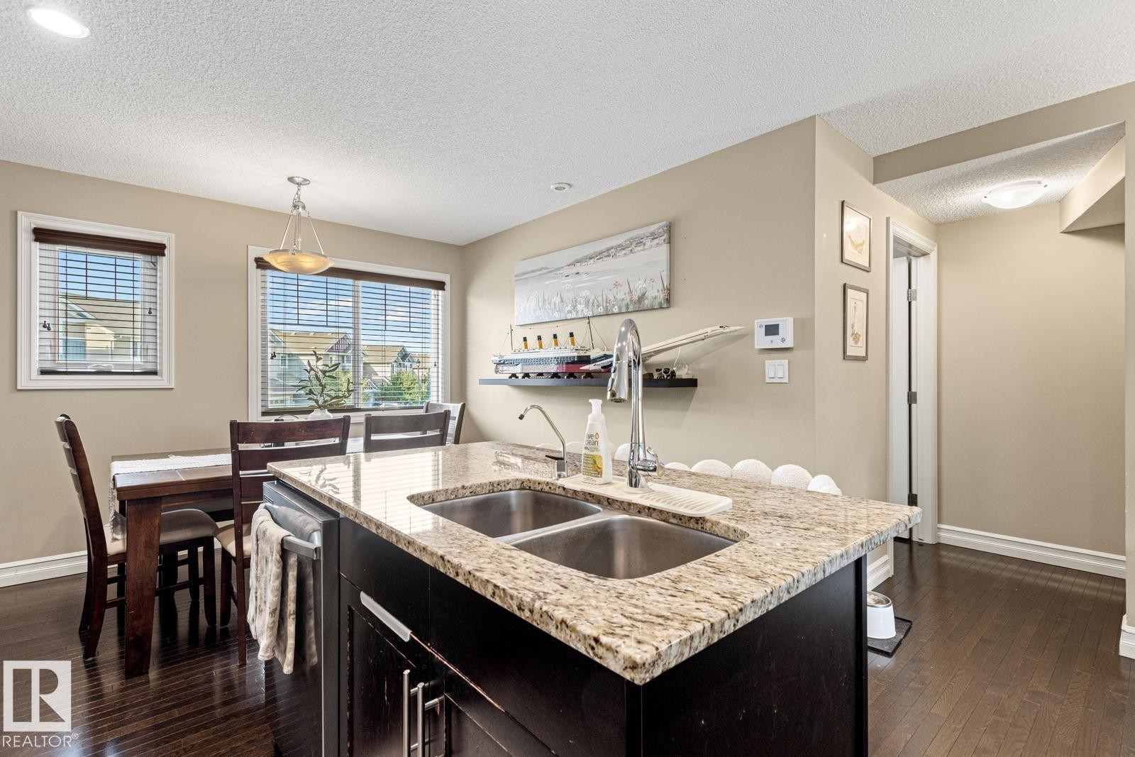 Kitchen island with granite countertop and double stainless-steel sink - 5319 3 Avenue Sw, Edmonton, AB