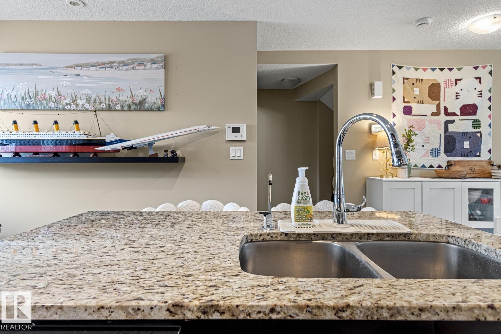 Spacious island with granite-finish countertop, dual basin stainless steel sink, and gooseneck faucet - 5319 3 Avenue Sw, Edmonton, AB