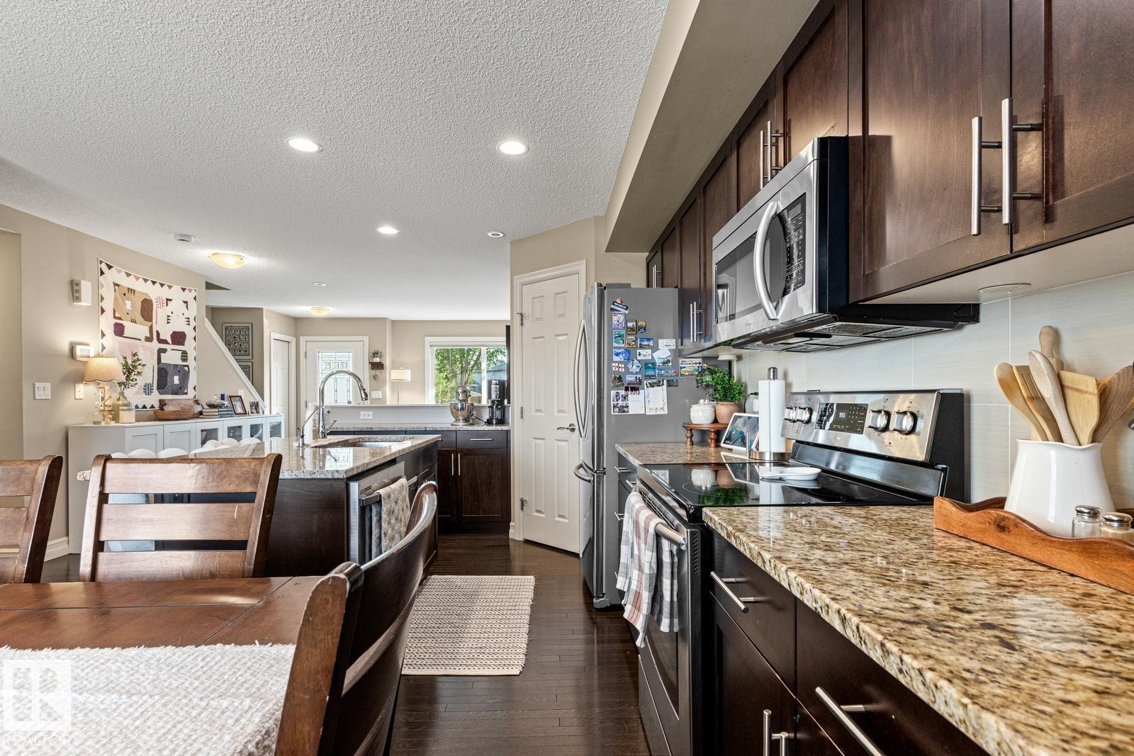Kitchen featuring stainless steel appliances, dark wood-finish cabinetry, and light-toned countertops - 5319 3 Avenue Sw, Edmonton, AB