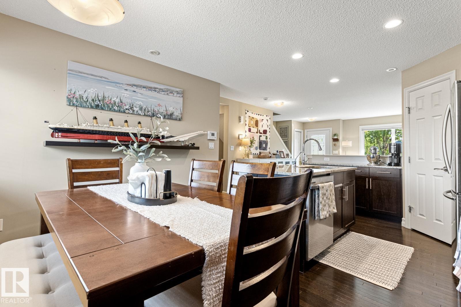 Hardwood flooring, recessed ceiling lighting, kitchen island with integrated sink, dark wood-finish cabinetry, and light-toned walls - 5319 3 Avenue Sw, Edmonton, AB