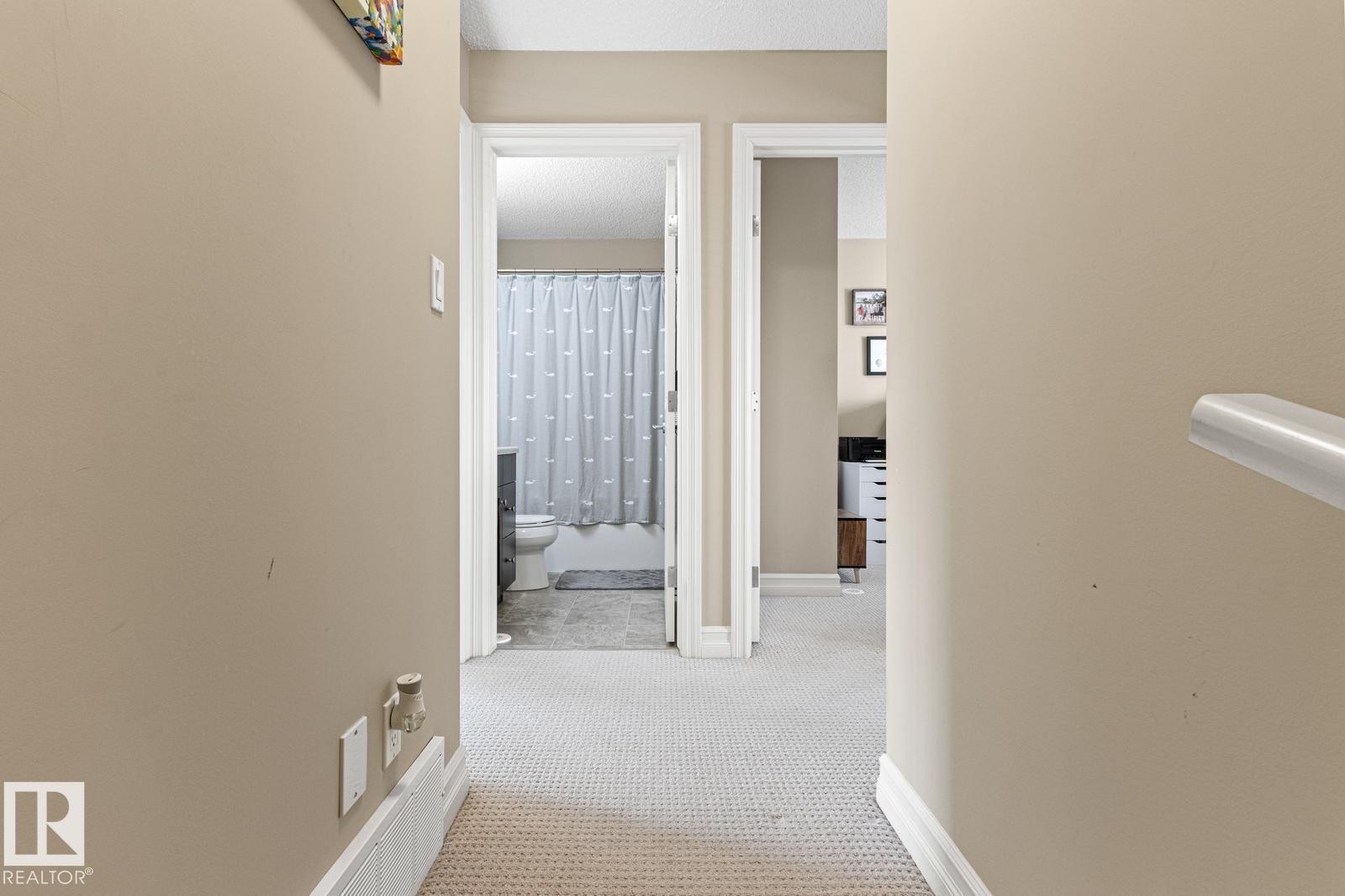 Hallway with light beige walls and patterned carpeting - 5319 3 Avenue Sw, Edmonton, AB