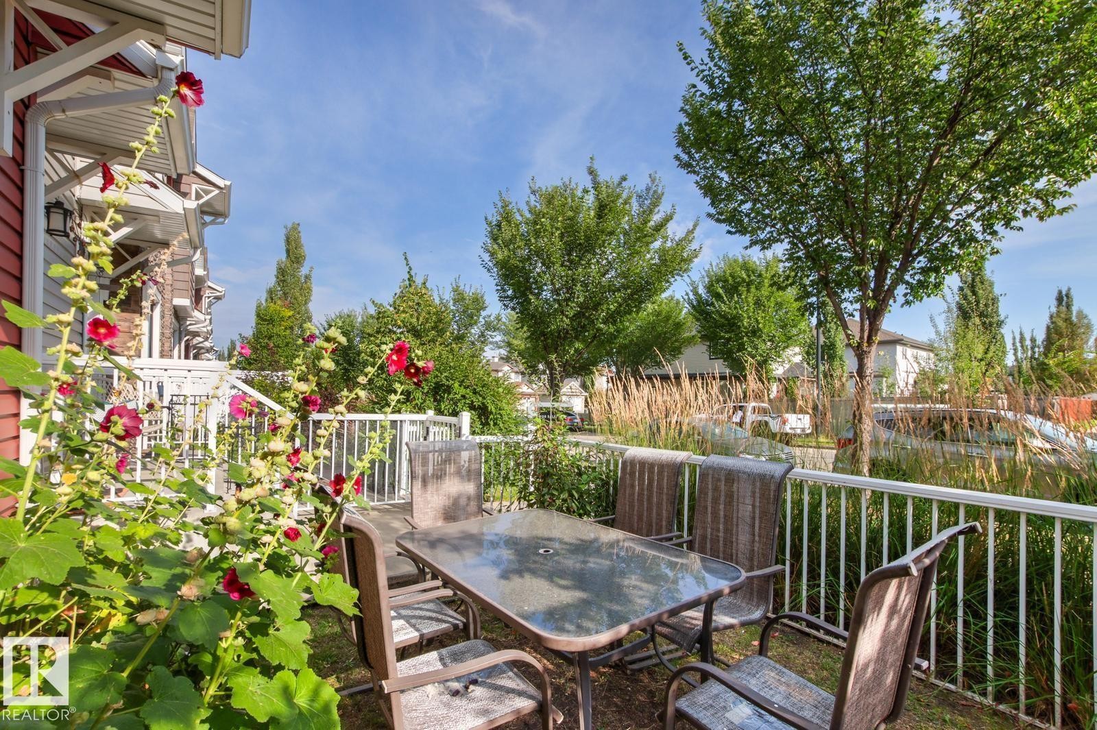 Patio space with white railings, mature trees, and landscaping - 5319 3 Avenue Sw, Edmonton, AB