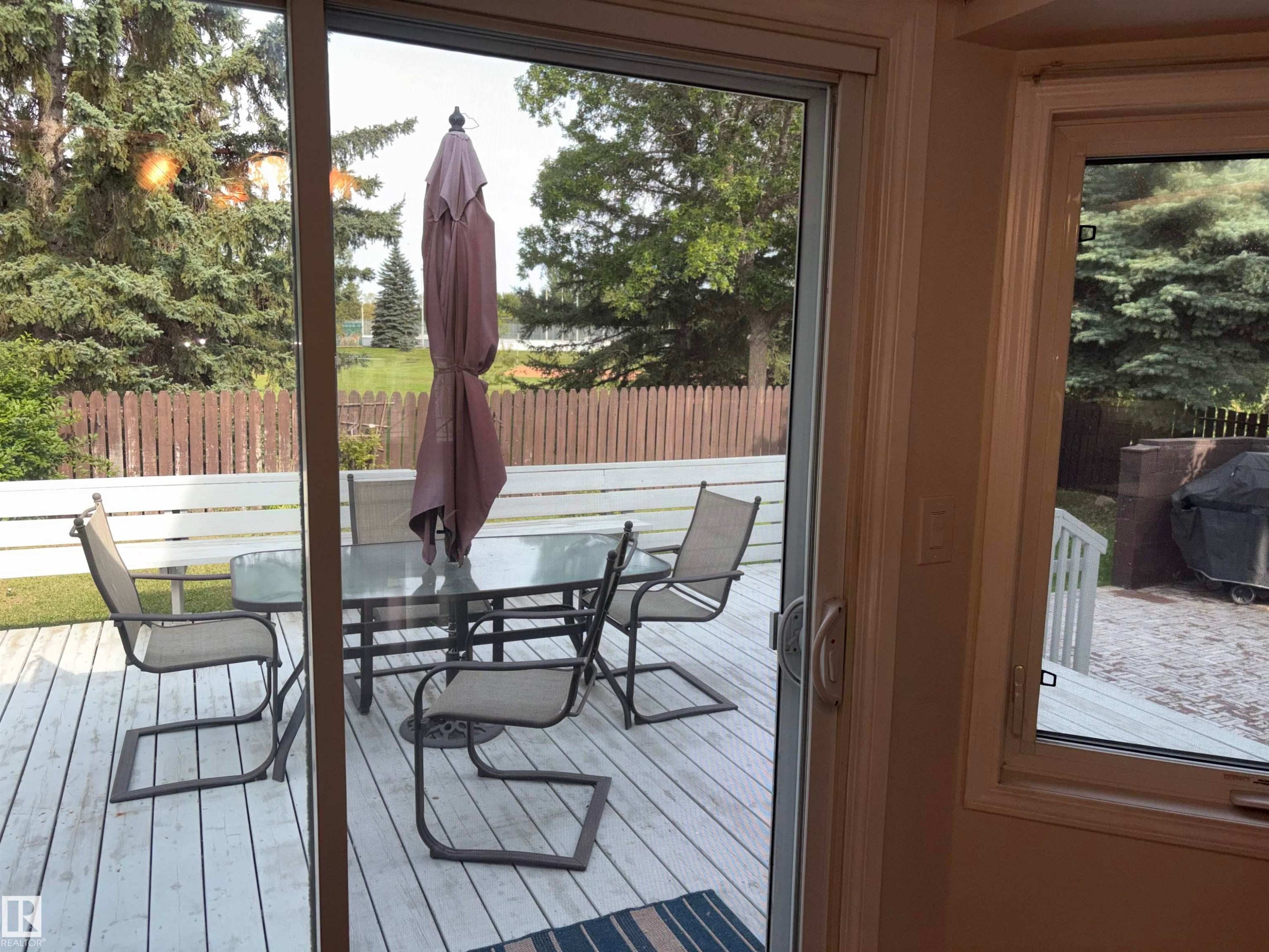 Sliding glass door leading to a wood deck with a privacy fence - 4027 74 Street Nw, Edmonton, AB