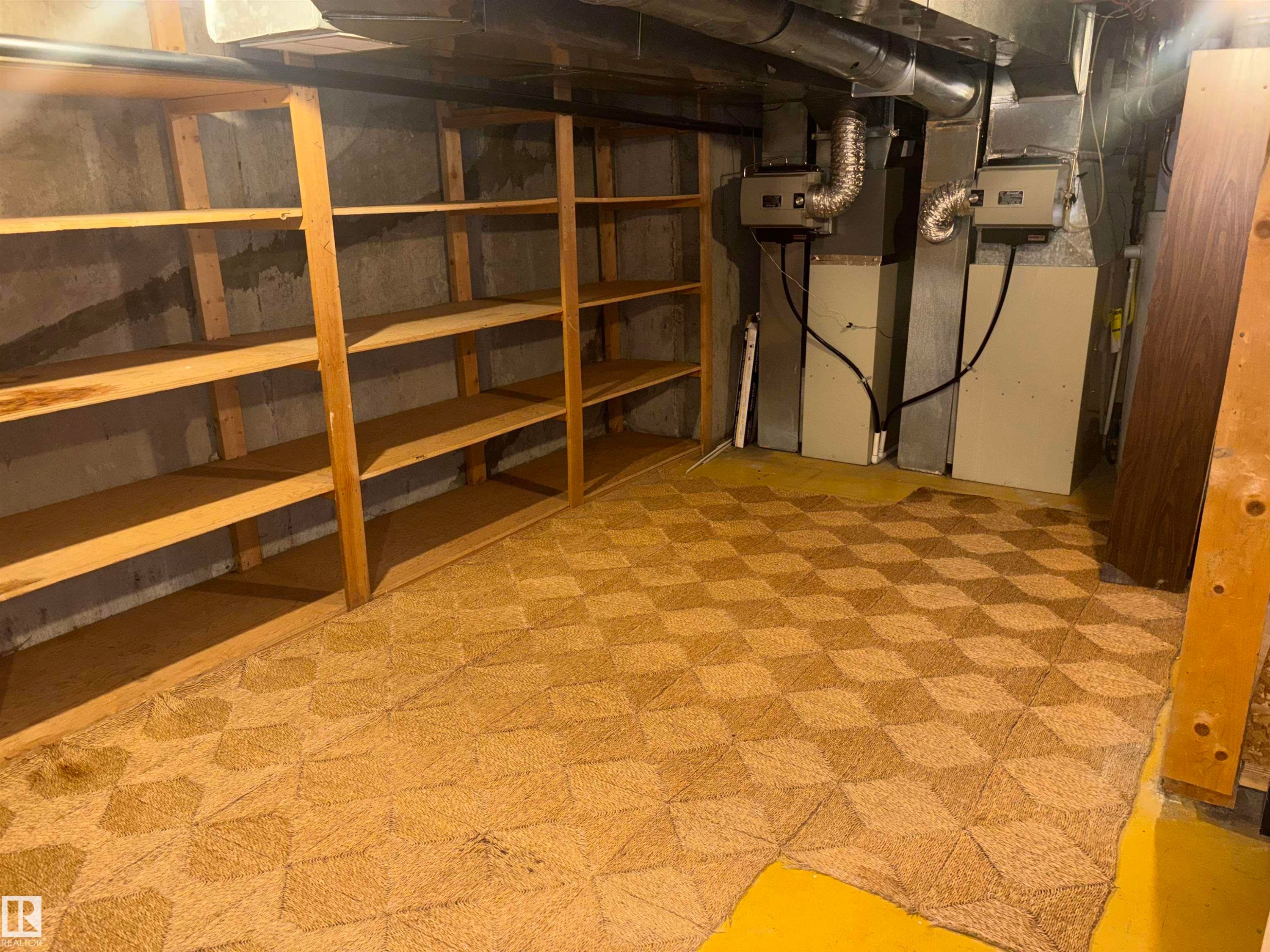 Built-in wood shelving, exposed ceiling ductwork, concrete wall, and patterned floor covering - 4027 74 Street Nw, Edmonton, AB