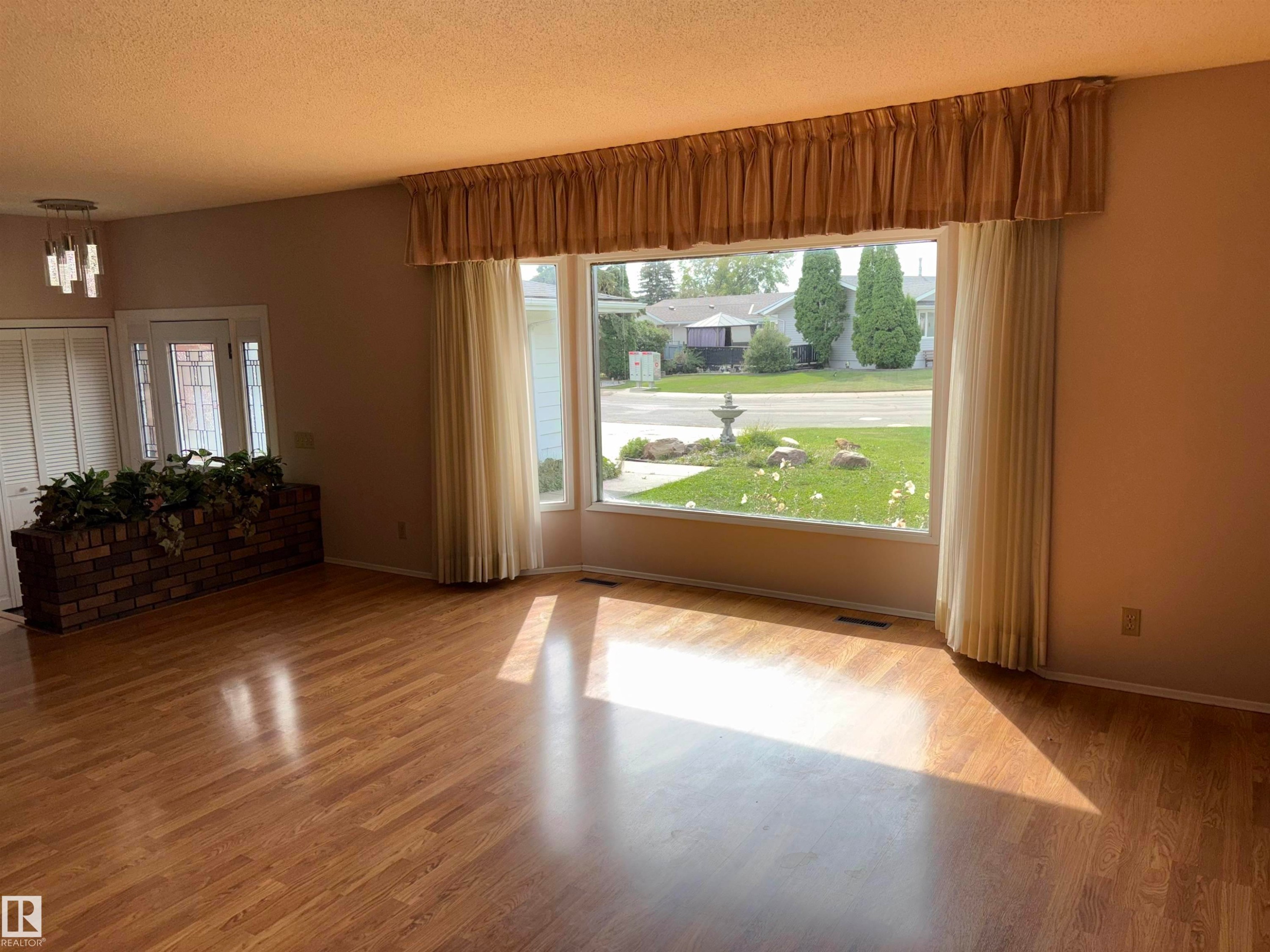 Wood-finish flooring, a large bay window, a brick planter, and a contemporary chandelier - 4027 74 Street Nw, Edmonton, AB