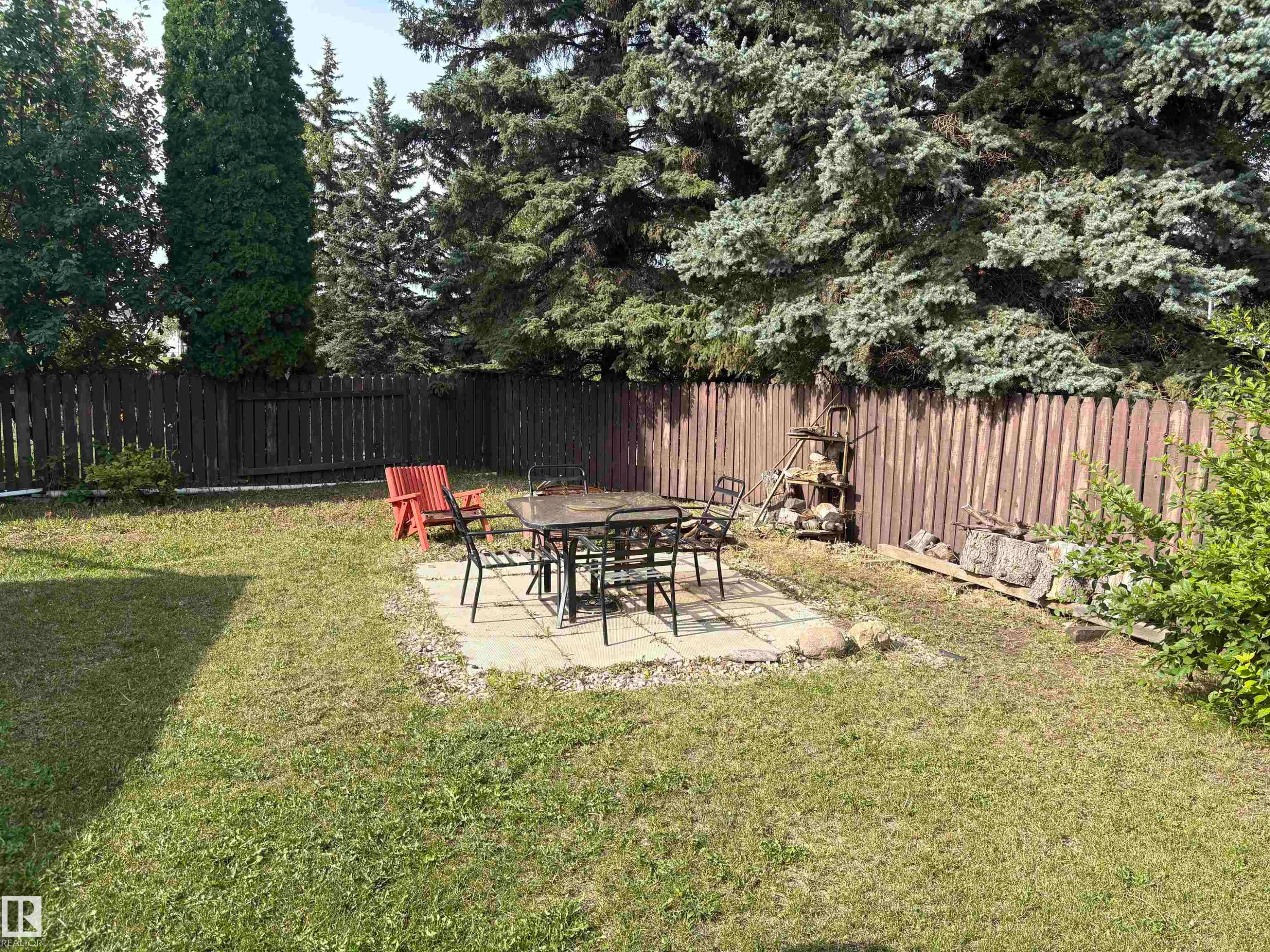 Fenced backyard featuring a paved patio and mature trees - 4027 74 Street Nw, Edmonton, AB