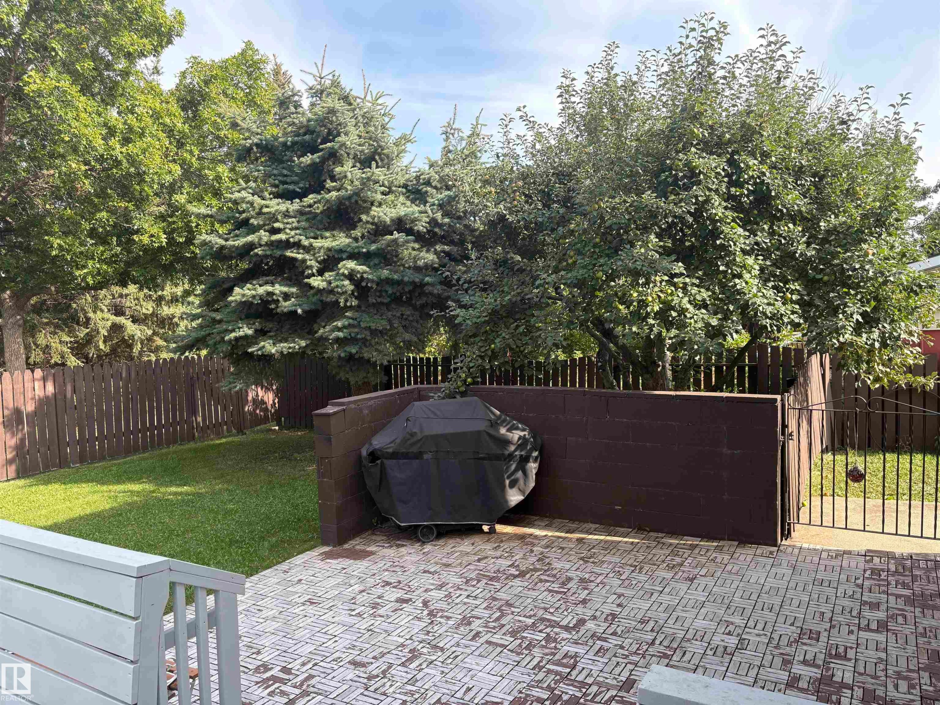 Patio featuring patterned paver flooring, privacy wall, and iron gate - 4027 74 Street Nw, Edmonton, AB