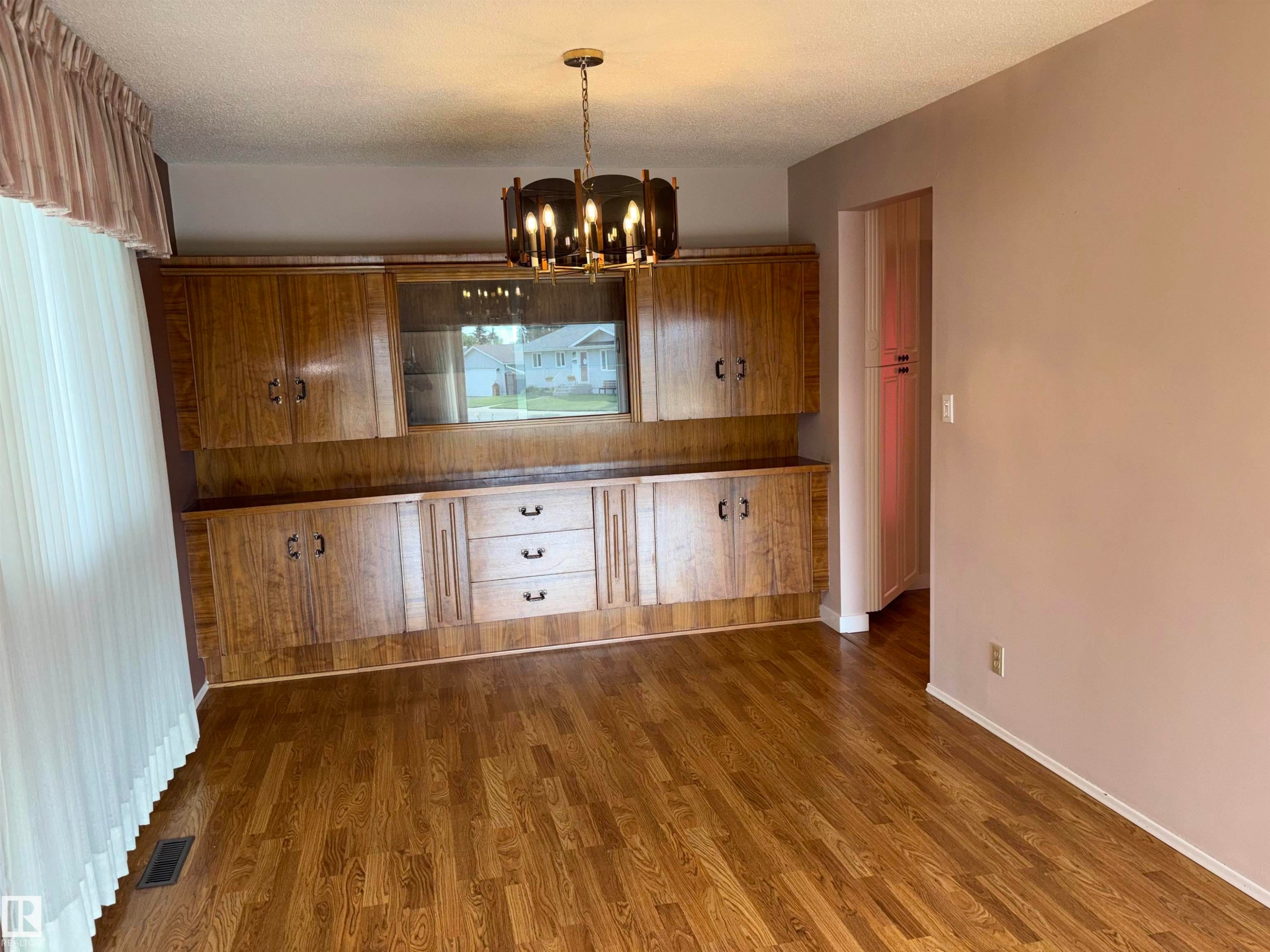 Wood-finish flooring, built-in wooden cabinetry with glass-front storage, and a ceiling-mounted light fixture - 4027 74 Street Nw, Edmonton, AB