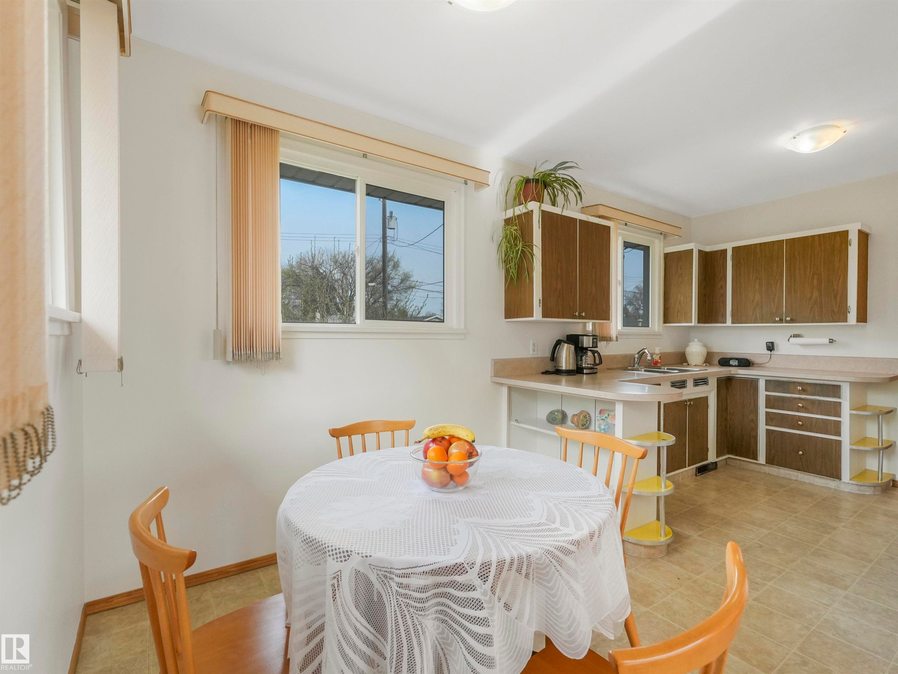 Kitchen featuring wood-finish cabinetry, tile flooring, and a sink with an attached faucet - 12614 69 Street Nw, Edmonton, AB