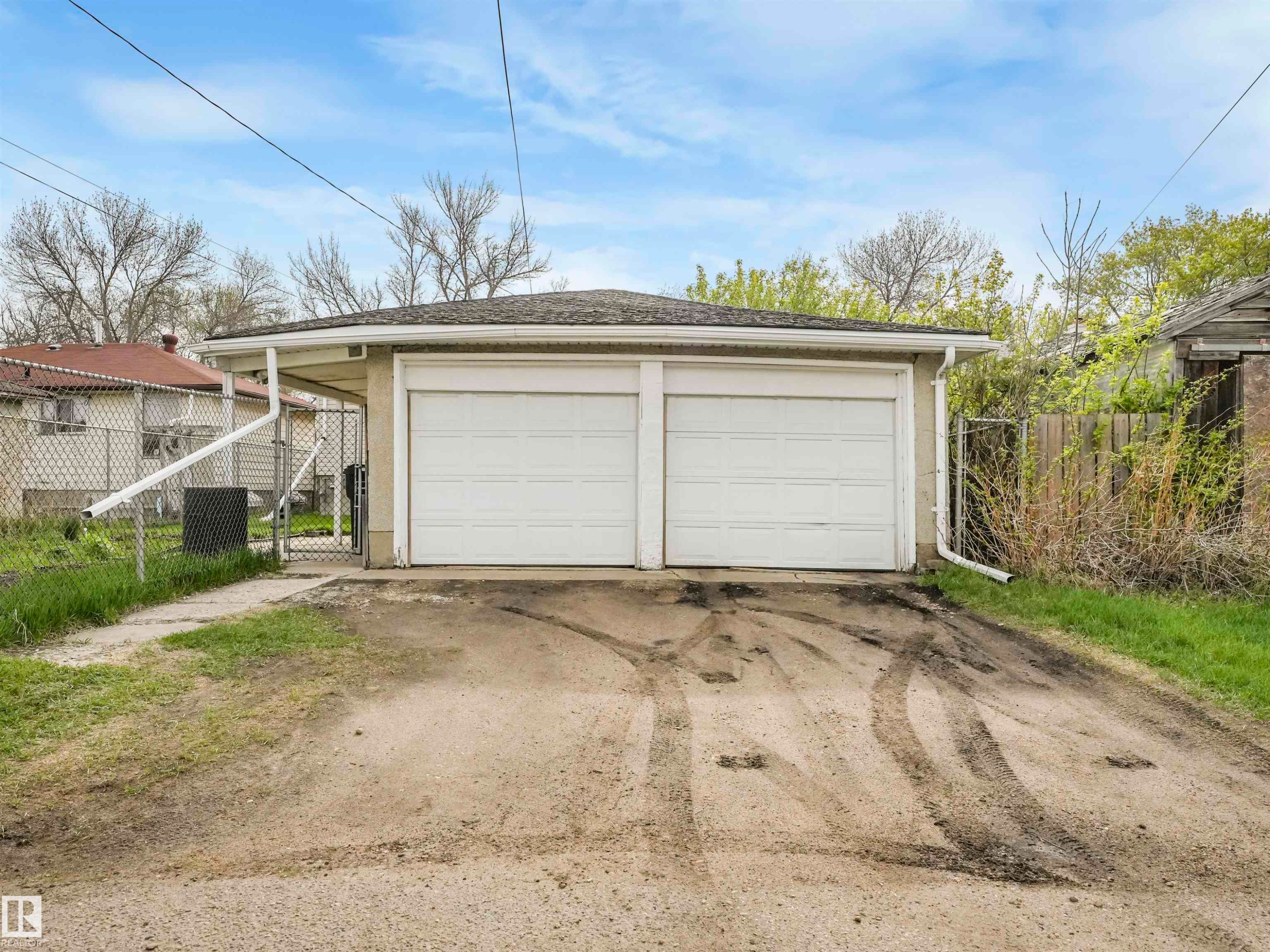 Two-car garage with white overhead doors and a gravel driveway - 12614 69 Street Nw, Edmonton, AB