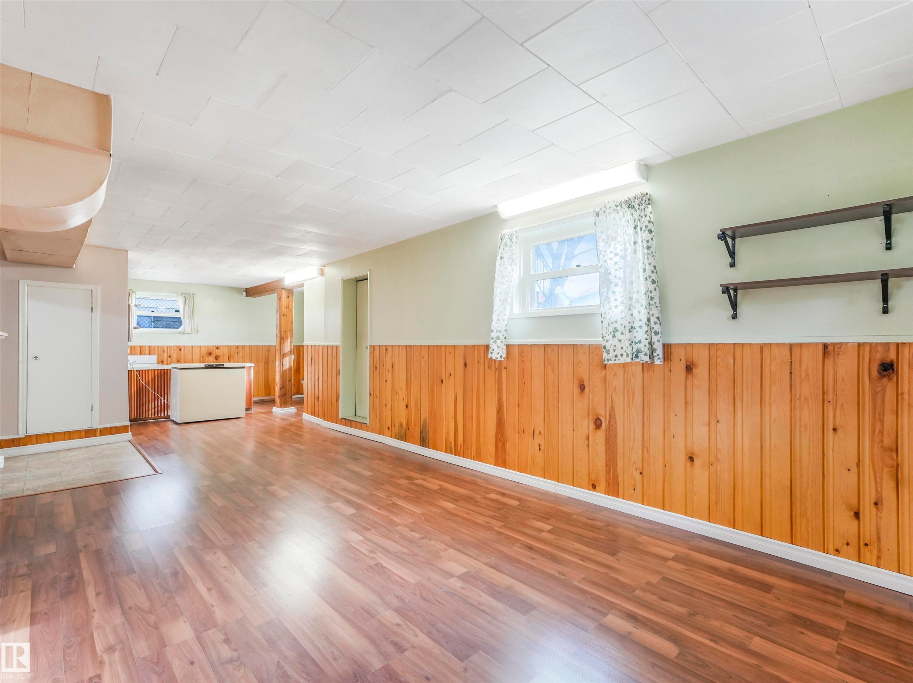 Wood-finish flooring, wood paneling, paneled drop ceiling, and a window for natural light - 12614 69 Street Nw, Edmonton, AB