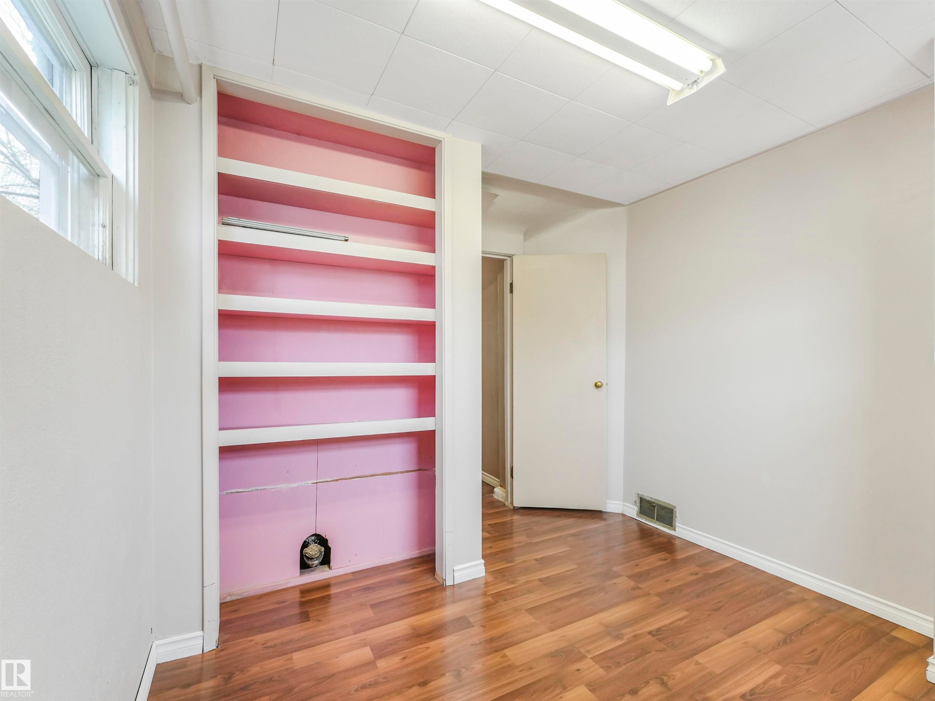 Wood-finish flooring, built-in shelving, white trim, and a drop ceiling with fluorescent lighting - 12614 69 Street Nw, Edmonton, AB