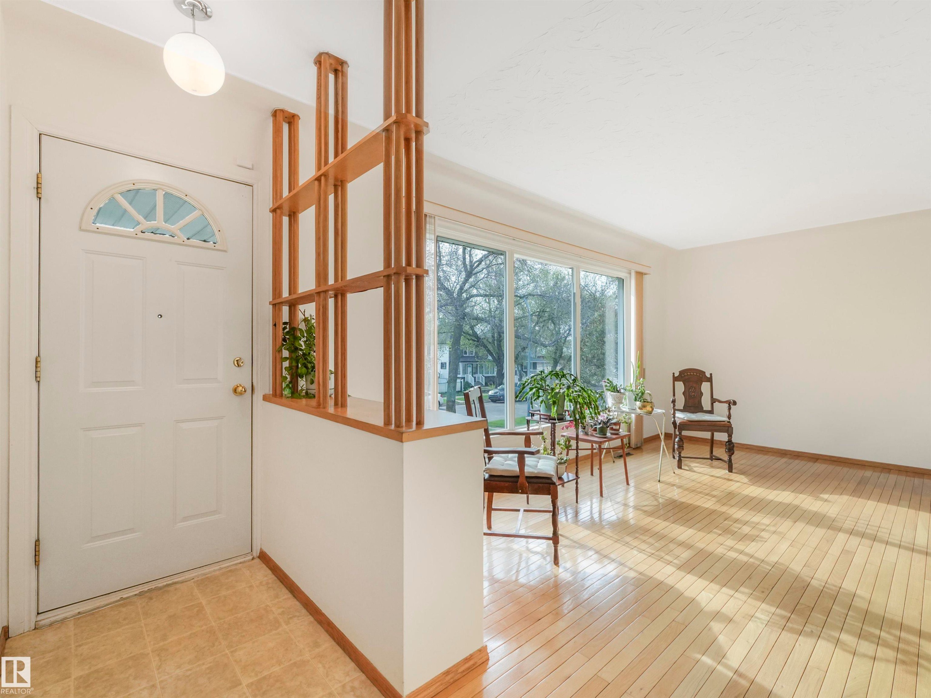 Front entry with a decorative half-moon window, tiled flooring, and a wood slat room divider - 12614 69 Street Nw, Edmonton, AB