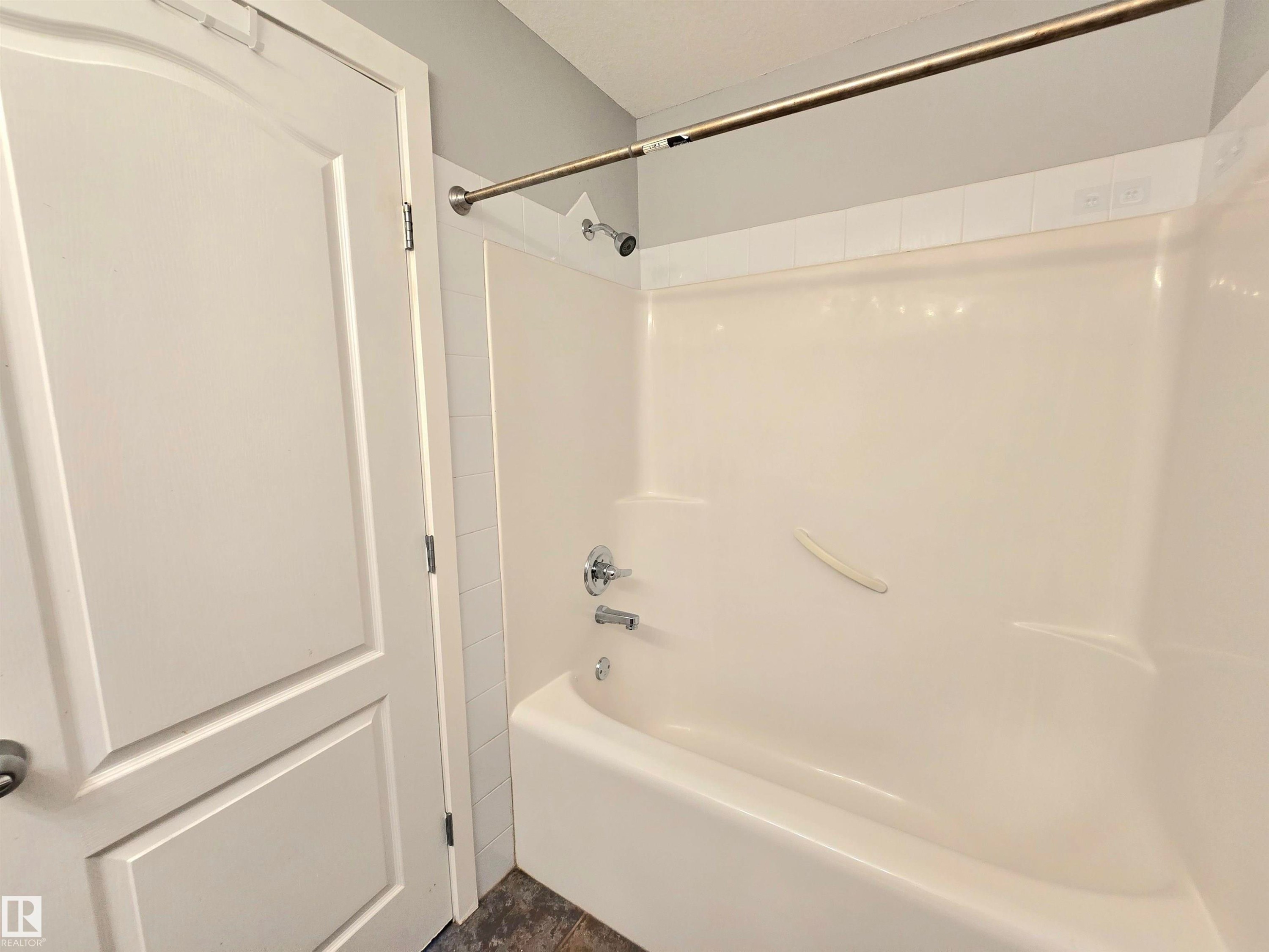 Tub and shower combination with chrome fixtures - #105 155 Edwards Dr Sw, Edmonton, AB - Indoor Photo Showing Bathroom