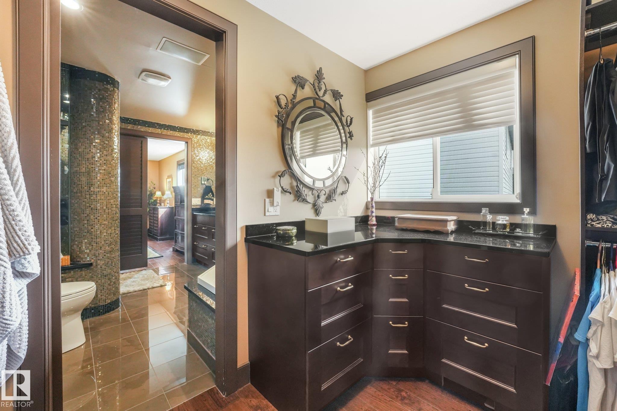 Custom cabinetry with dark countertops, a large window with blinds, and rich wood-finish flooring - 12827 150 Avenue Nw, Edmonton, AB