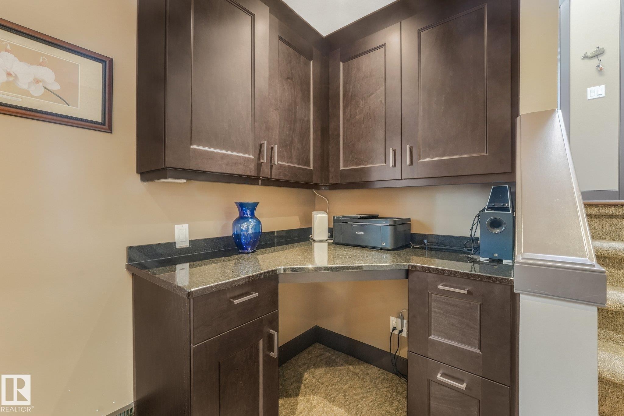 Built-in desk area with dark wood cabinetry and a stone countertop - 12827 150 Avenue Nw, Edmonton, AB