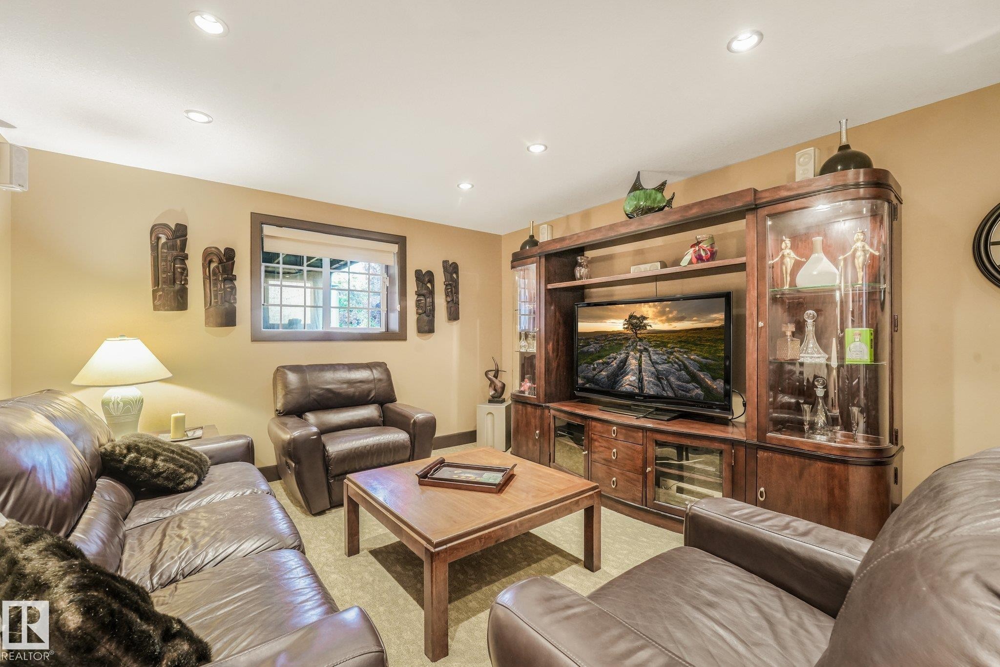 Recessed lighting, wood-trimmed window, built-in entertainment center with display cabinets, and neutral wall tones - 12827 150 Avenue Nw, Edmonton, AB