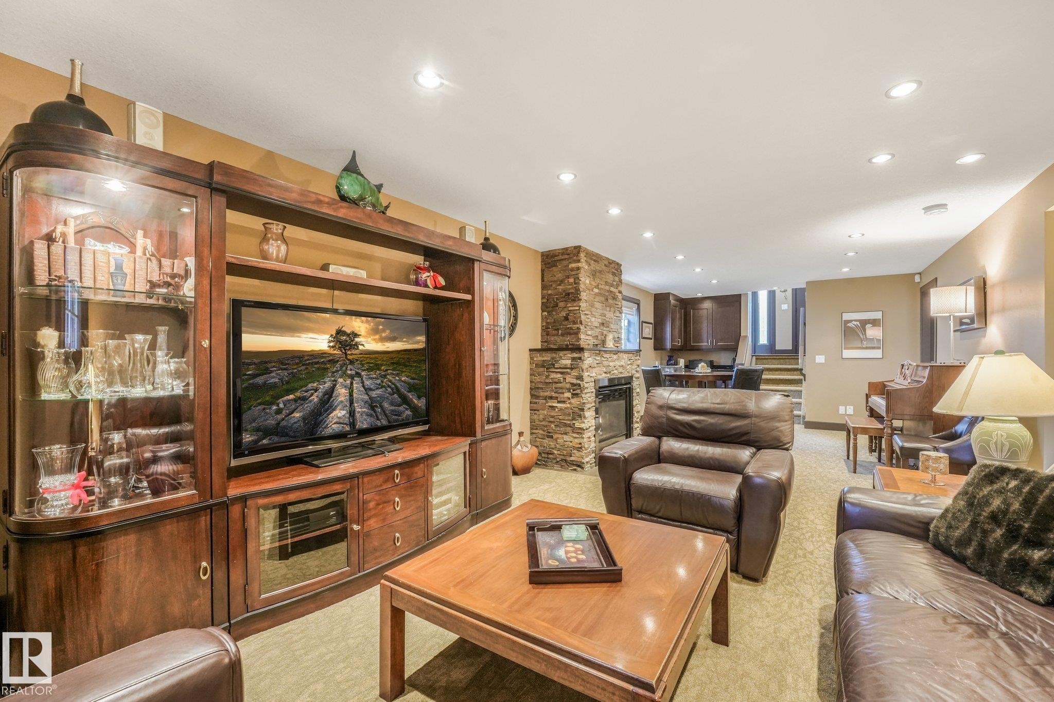 Recessed lighting, stacked stone fireplace, built-in media cabinetry, wood-finish coffee table, and wood-finish side table - 12827 150 Avenue Nw, Edmonton, AB