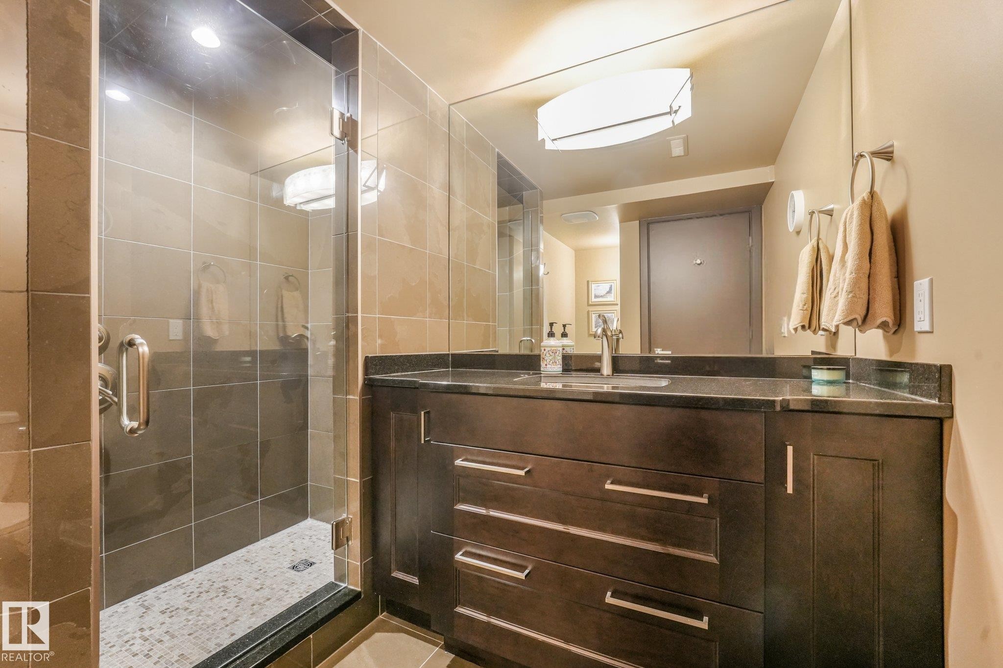 Glass-enclosed shower with tiled walls and pebble-finish floor - 12827 150 Avenue Nw, Edmonton, AB