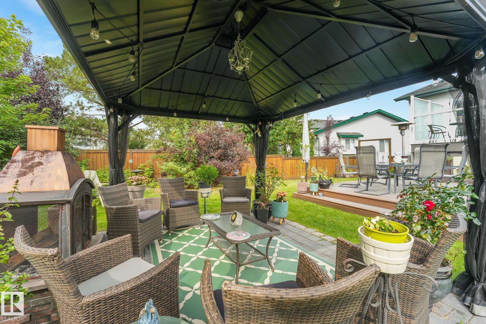 Outdoor gazebo with integrated lighting, paver patio, freestanding outdoor fireplace, and a raised wood deck - 12827 150 Avenue Nw, Edmonton, AB