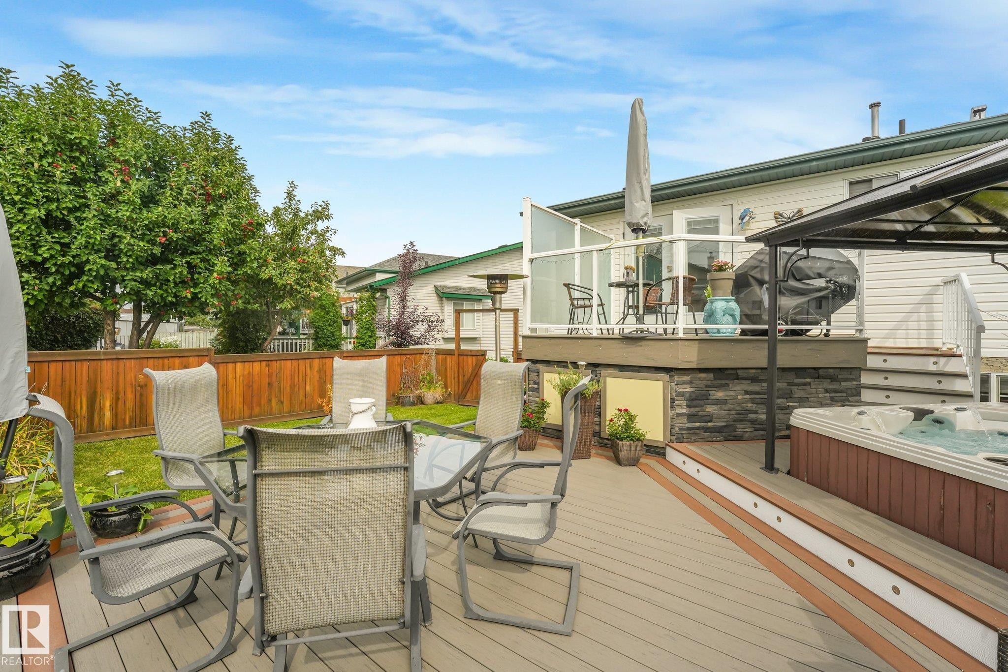 Multi-level composite deck with integrated lighting, a built-in hot tub, and glass panel railing - 12827 150 Avenue Nw, Edmonton, AB