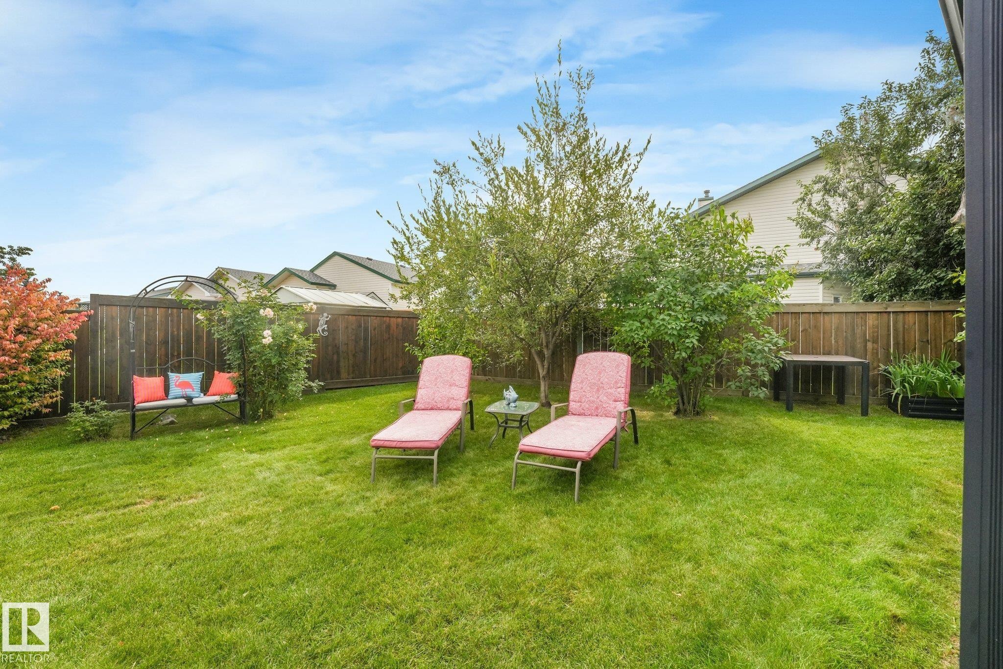 Expansive lawn area, established perimeter fencing, mature shrubs, and surrounding foliage - 12827 150 Avenue Nw, Edmonton, AB