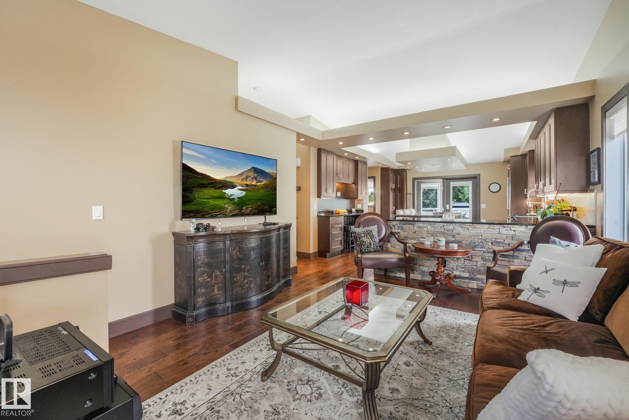 Hardwood flooring, recessed lighting, stone accent wall, tray ceiling, and built-in cabinetry - 12827 150 Avenue Nw, Edmonton, AB