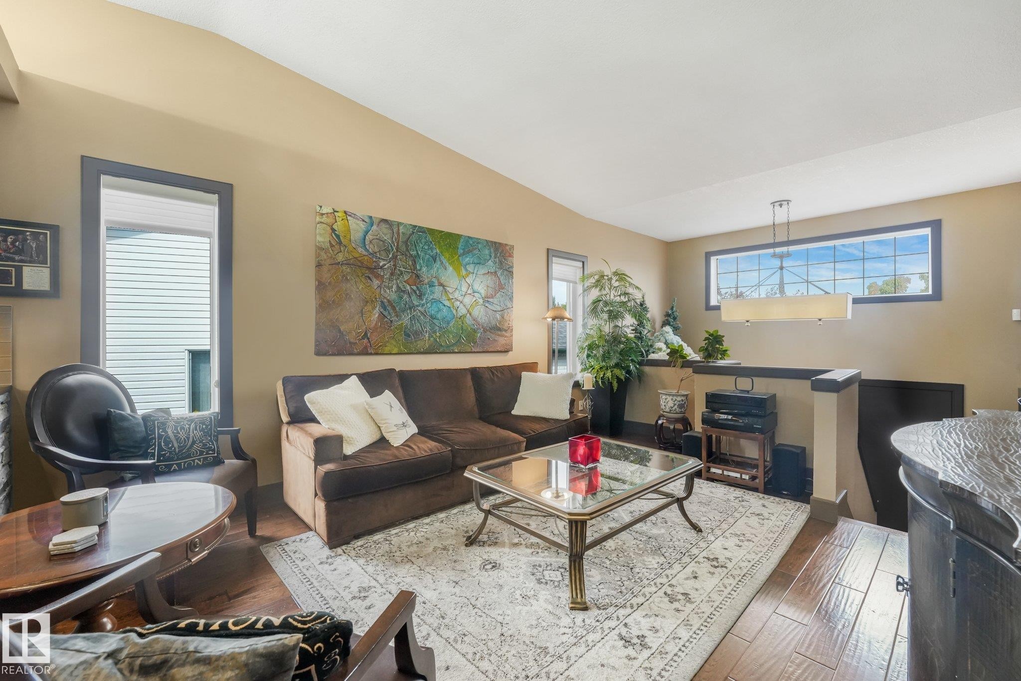 Vaulted ceiling with a flush-mount linear light fixture, wood-finish flooring, and a large transom window - 12827 150 Avenue Nw, Edmonton, AB