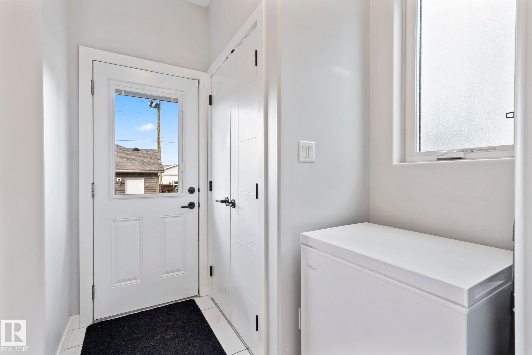 White paneled exterior door with glass insert, black hardware, and tiled flooring - 10338 162St Nw, Edmonton, AB