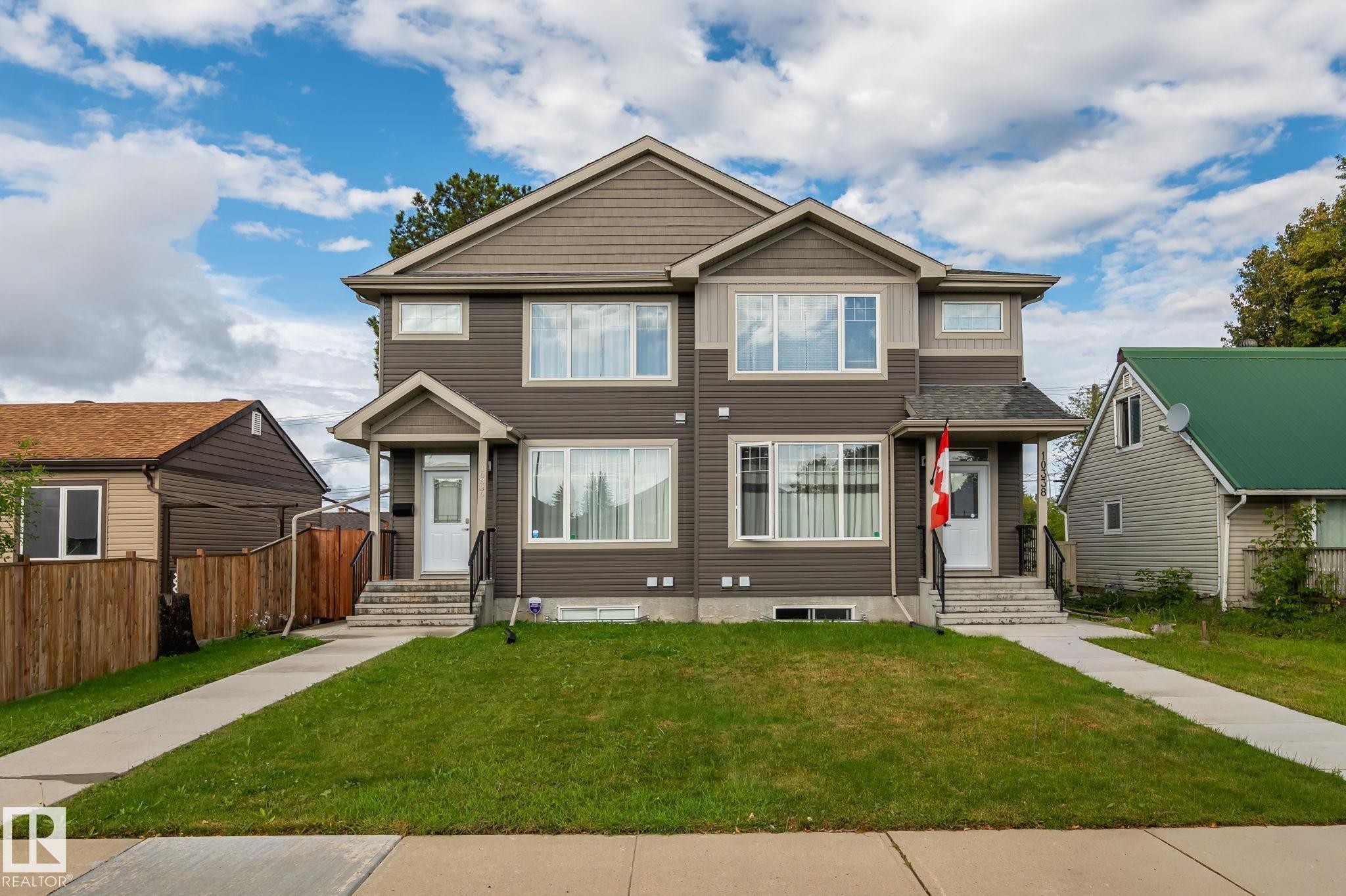 Modern duplex featuring a two-tone facade, prominent gables, covered entryways, and concrete front walkways - 10338 162St Nw, Edmonton, AB
