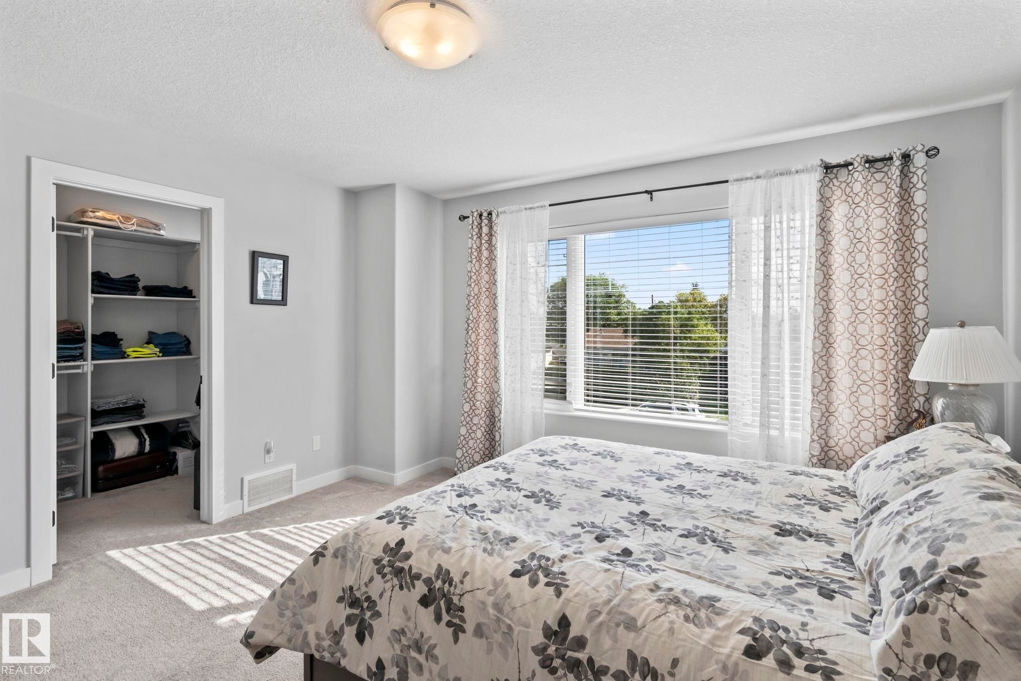 Recessed closet with built-in shelving, large window with blinds, light-colored walls, and neutral carpeting - 10338 162St Nw, Edmonton, AB