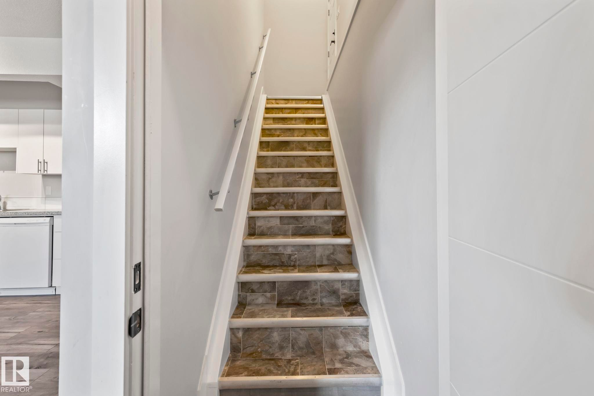 Staircase with tile risers and treads, featuring a white handrail - 10338 162St Nw, Edmonton, AB