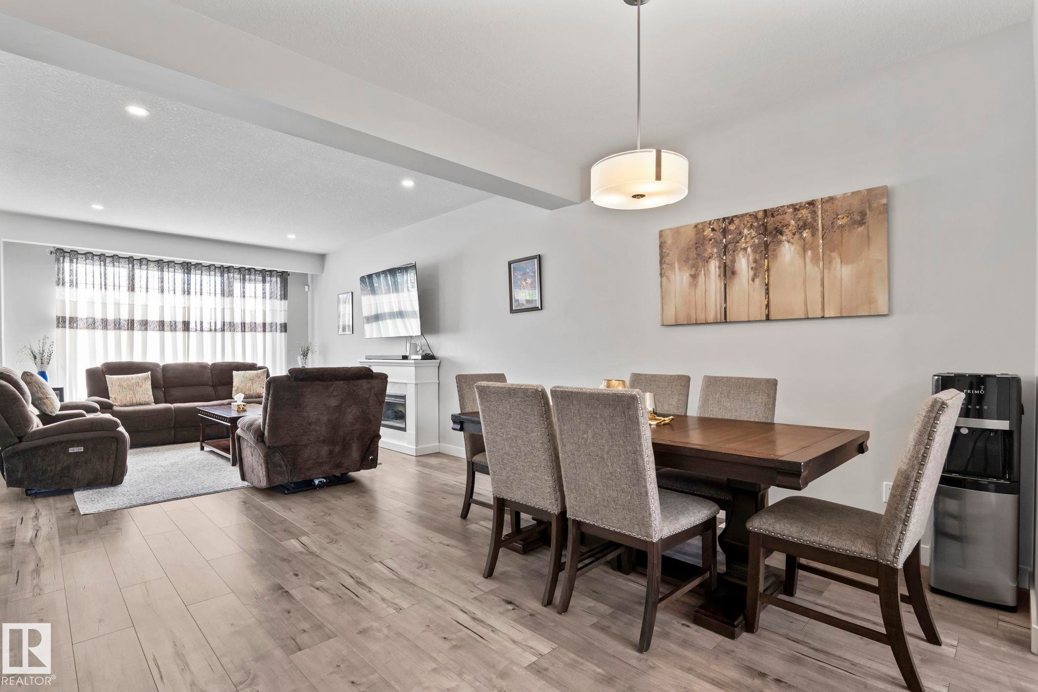 Open-concept living space with wood-finish flooring, a contemporary fireplace, and recessed lighting - 10338 162St Nw, Edmonton, AB