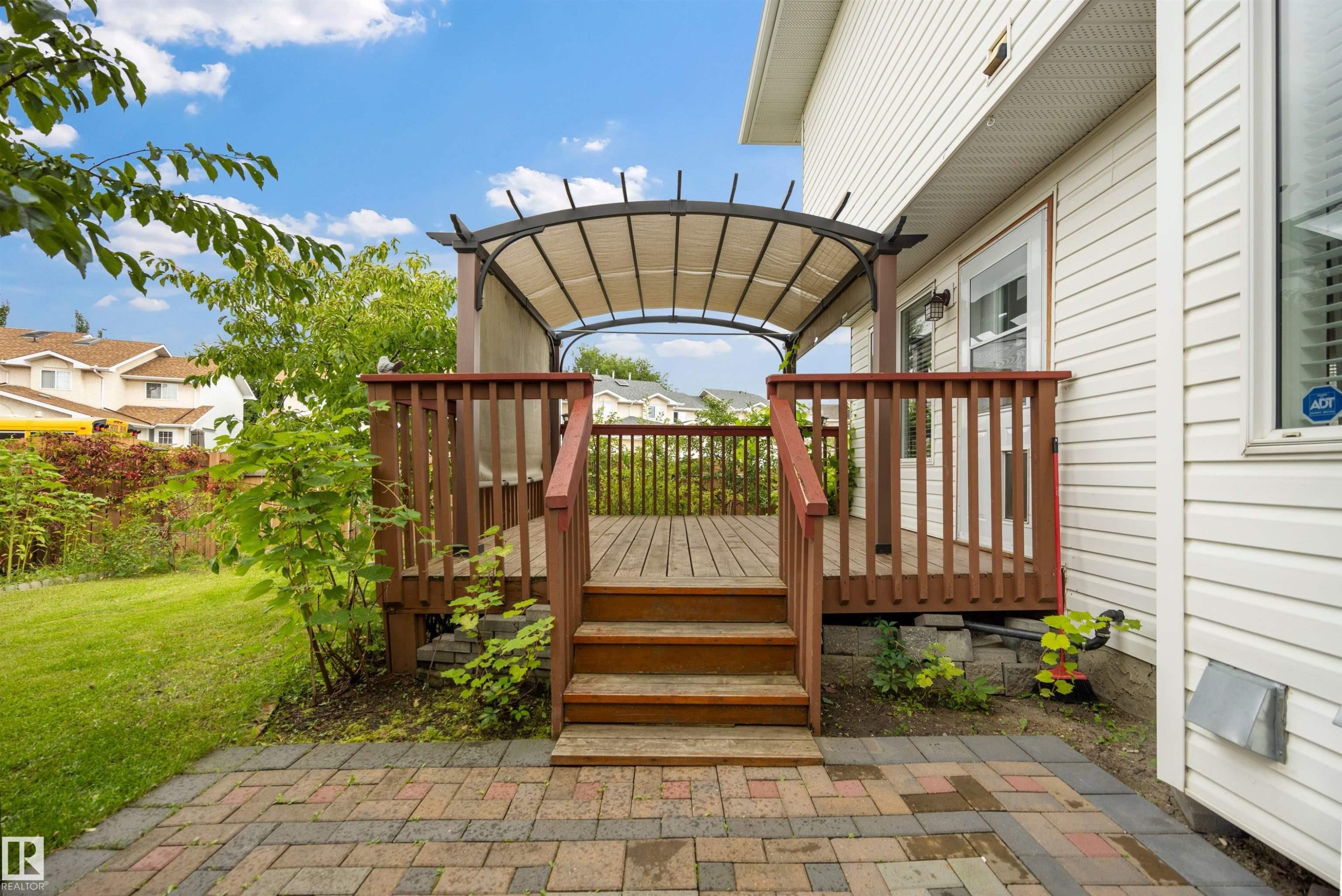 View of back yard with fruit trees, deck and stone patio - 6910 158A Avenue Nw, Edmonton, AB