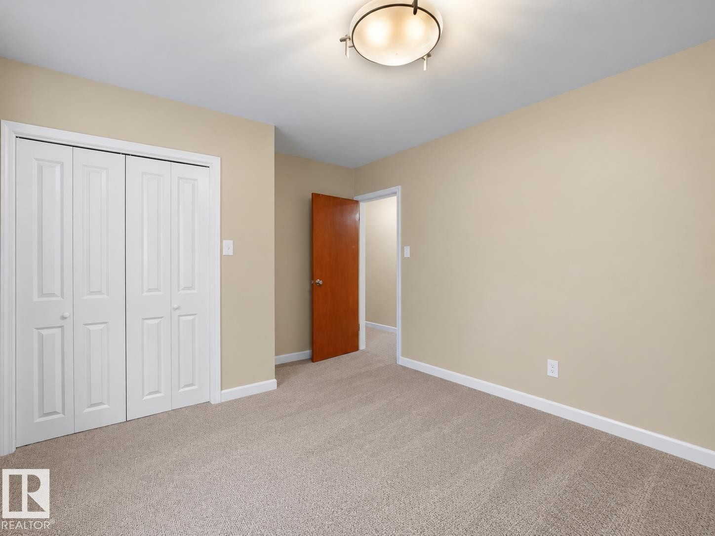 Plush carpet flooring, neutral paint palette, white bi-fold closet doors, and an overhead flush-mount light fixture - 12002 48 Street Nw, Edmonton, AB