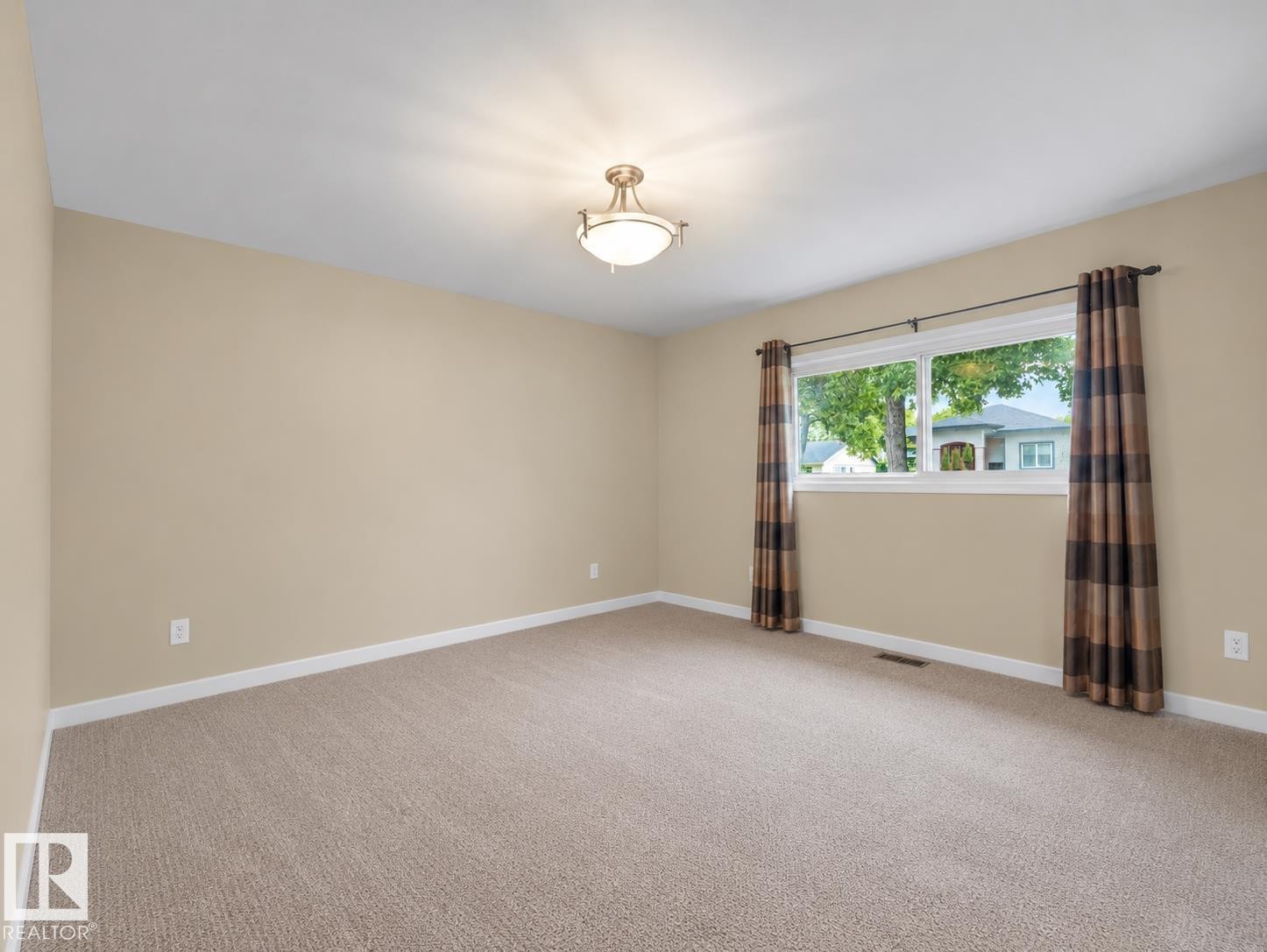 Neutral-toned walls, carpet flooring, a window with exterior visibility, and an overhead light fixture - 12002 48 Street Nw, Edmonton, AB
