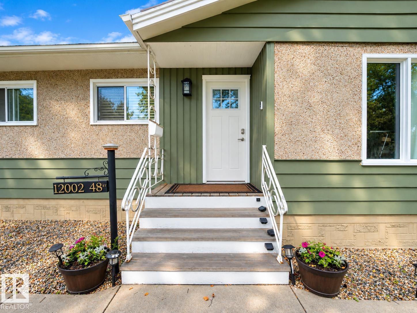 Entryway featuring a white paneled door with windowpanes, a dark sconce, and white railing - 12002 48 Street Nw, Edmonton, AB