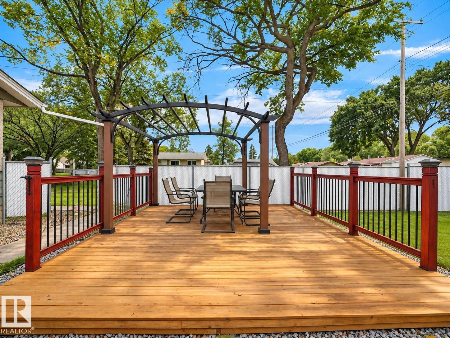 Expansive wood deck with a pergola, dark wood posts, and red-stained railings with black balusters - 12002 48 Street Nw, Edmonton, AB