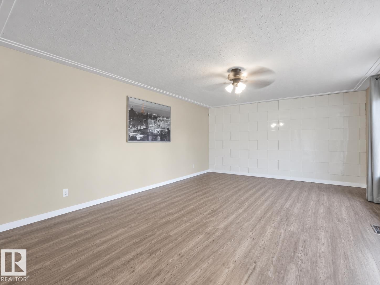 Wood-finish flooring, textured accent wall, ceiling fan with integrated lighting, and crown molding - 12002 48 Street Nw, Edmonton, AB