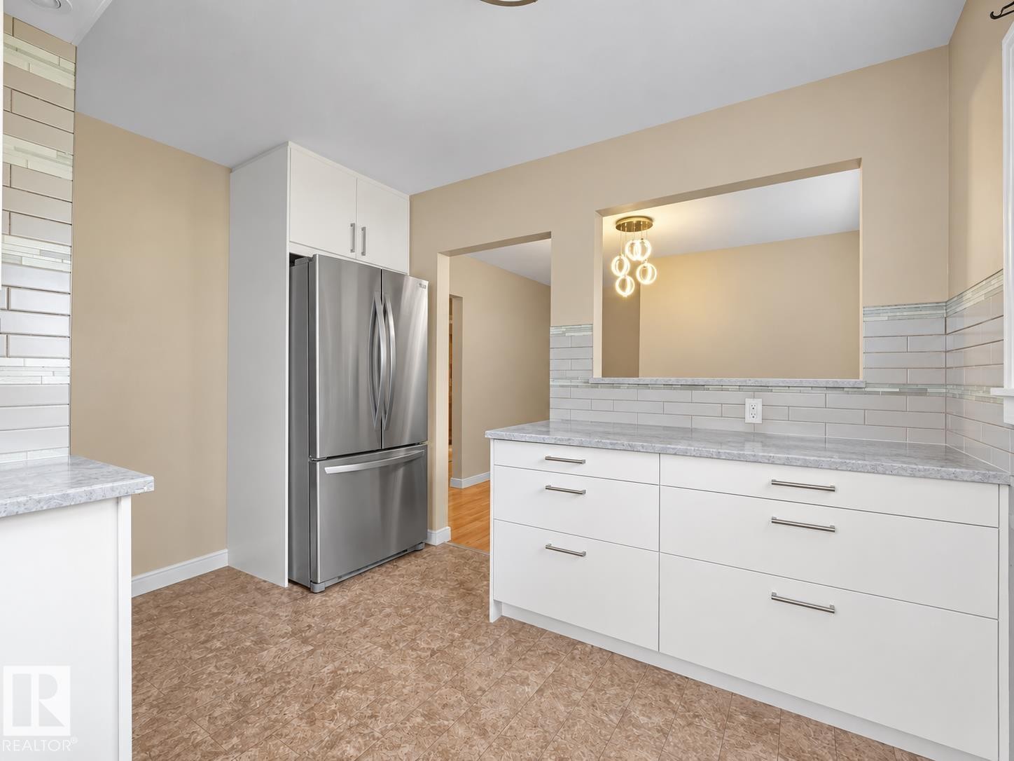 White cabinetry with brushed nickel hardware, stainless steel refrigerator, stone countertops, and tile backsplash - 12002 48 Street Nw, Edmonton, AB