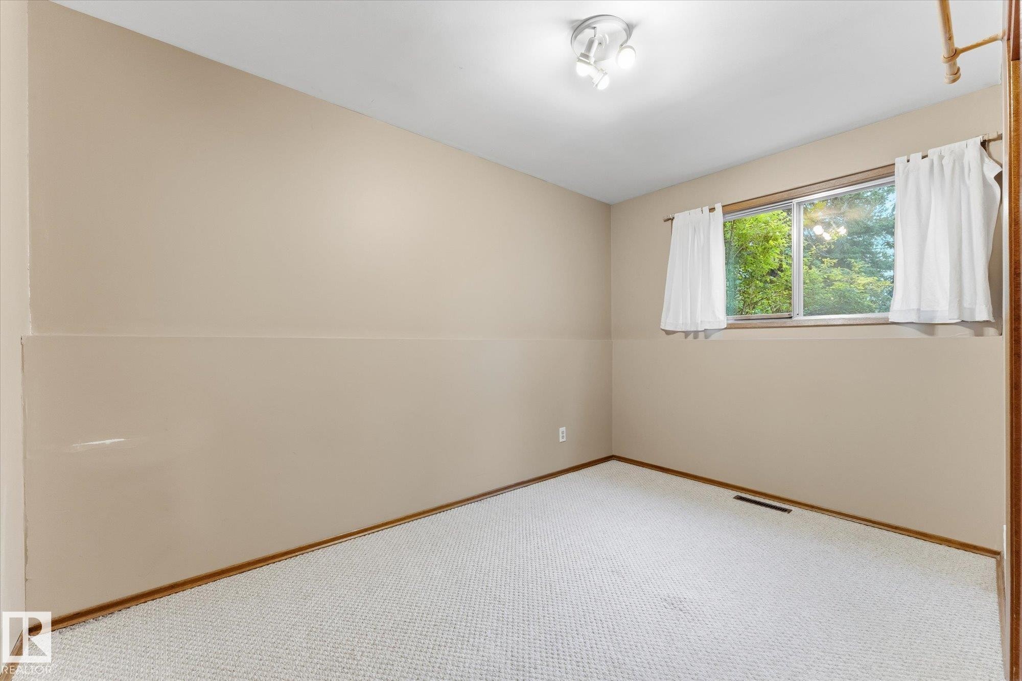 Recessed lighting, light beige walls, two-tone wall finish, and a window with a green outdoor scene - 11311 Malmo Road Nw, Edmonton, AB