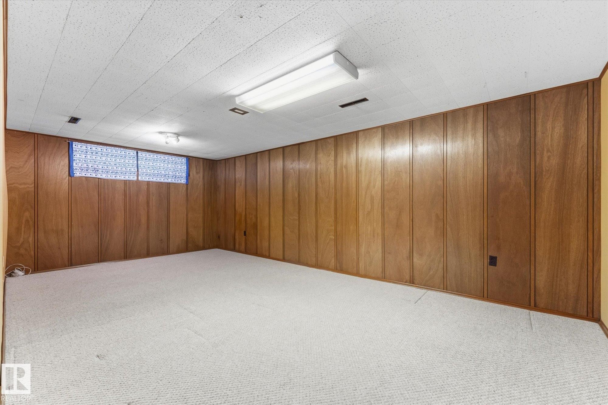 Wood-paneled walls with a textured ceiling and light-toned carpet flooring - 11311 Malmo Road Nw, Edmonton, AB