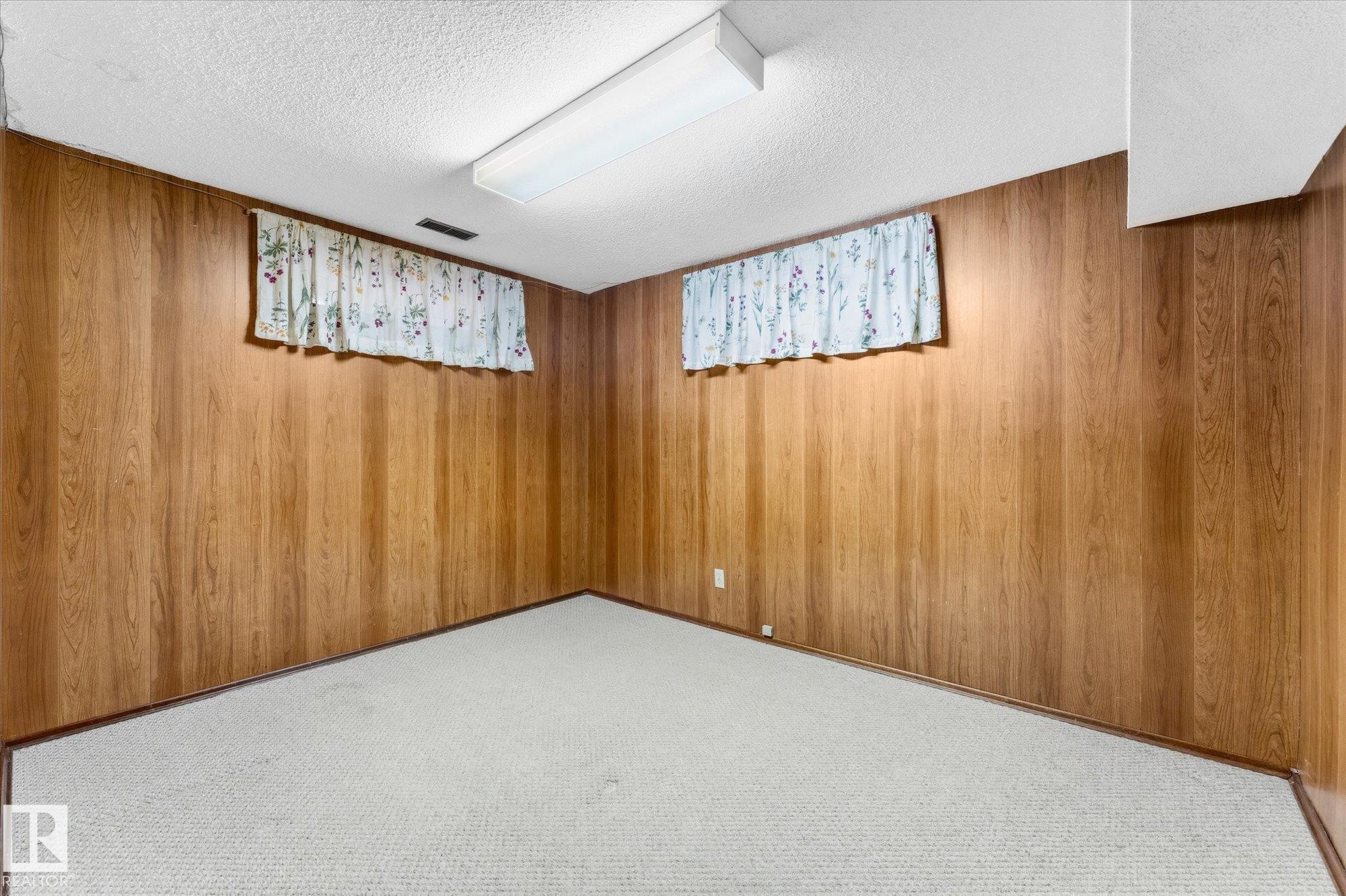 Wood-finish wall paneling, white textured ceiling, and light-colored carpet flooring - 11311 Malmo Road Nw, Edmonton, AB