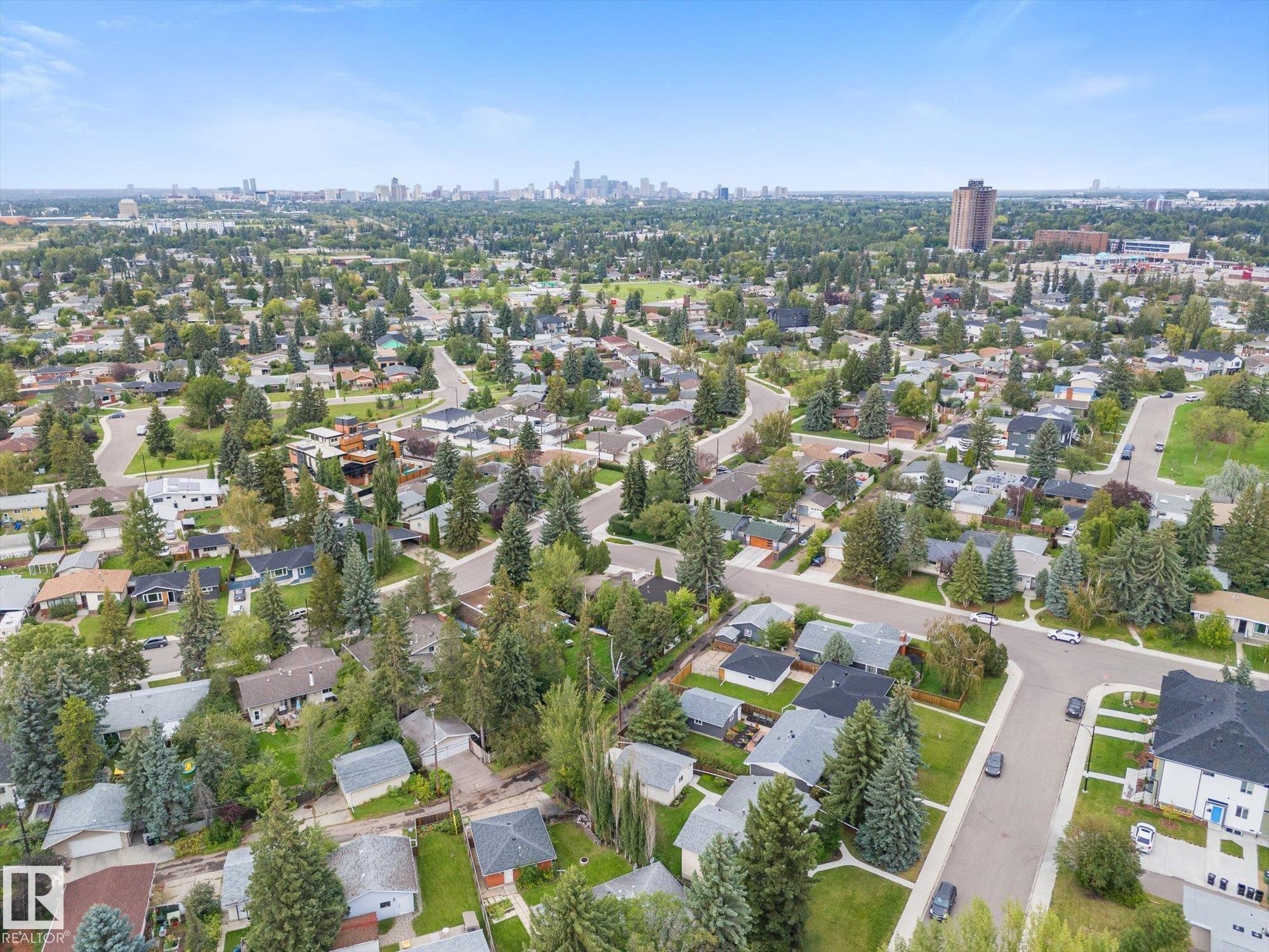 Mature treed neighborhood with residential properties and distant city skyline - 11311 Malmo Road Nw, Edmonton, AB