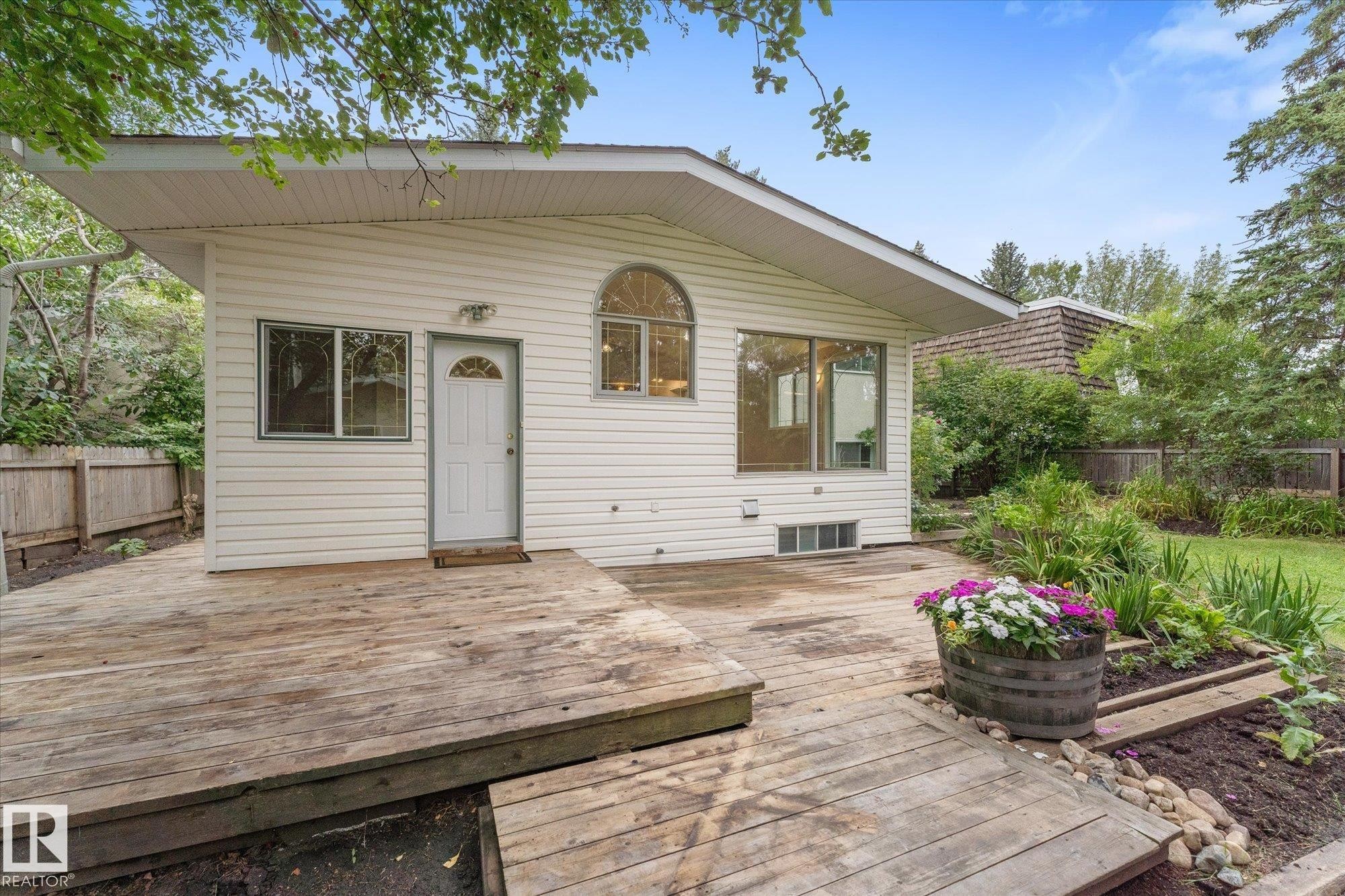 Exterior siding, large deck area, established landscaping, arched window, and a privacy fence - 11311 Malmo Road Nw, Edmonton, AB