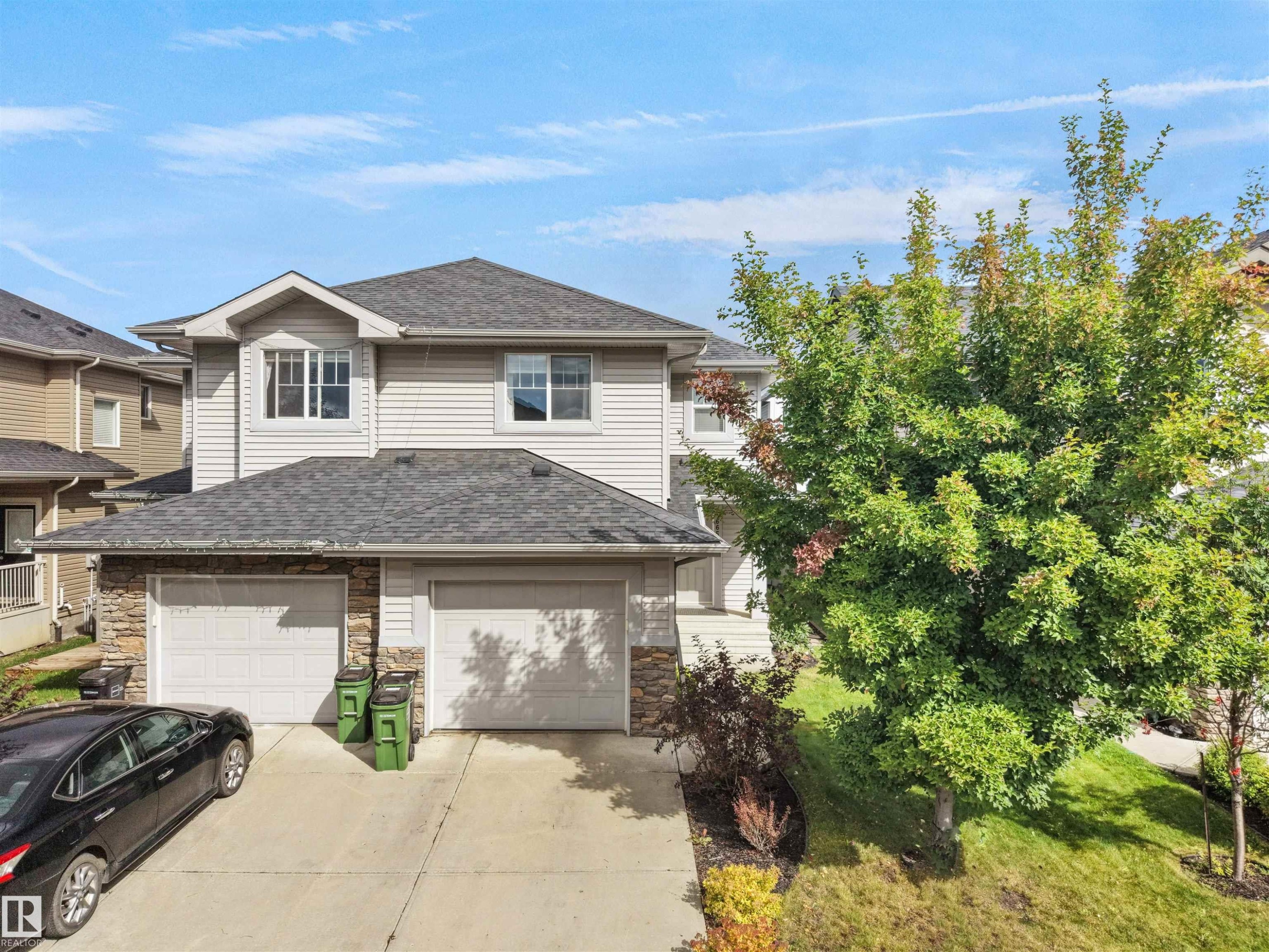 Siding exterior with stone accents, attached two-car garage, and established landscaping - 6656 Cardinal Rd Sw, Edmonton, AB