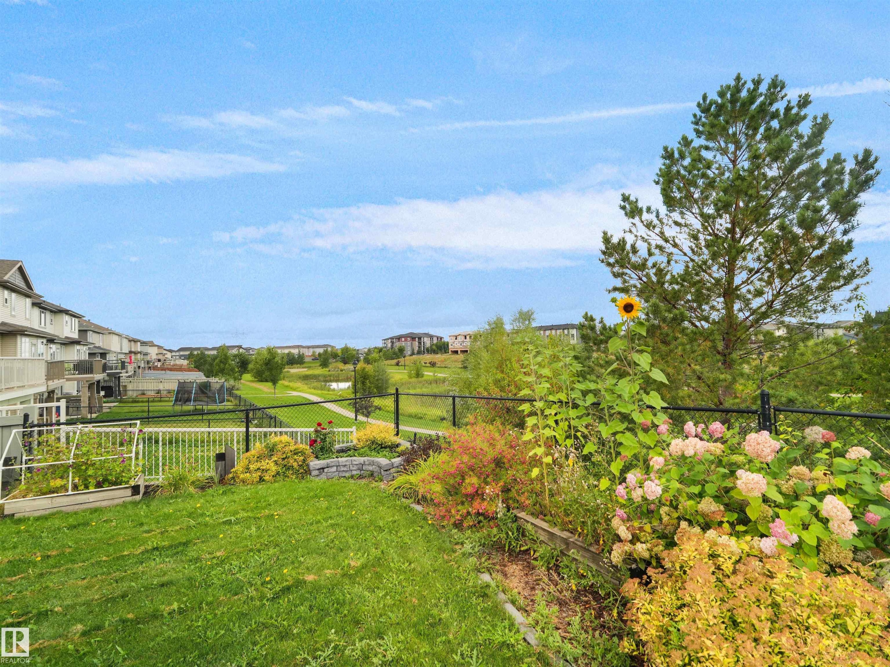 Expansive backyard with manicured lawn, established garden beds, and mature trees - 6656 Cardinal Rd Sw, Edmonton, AB