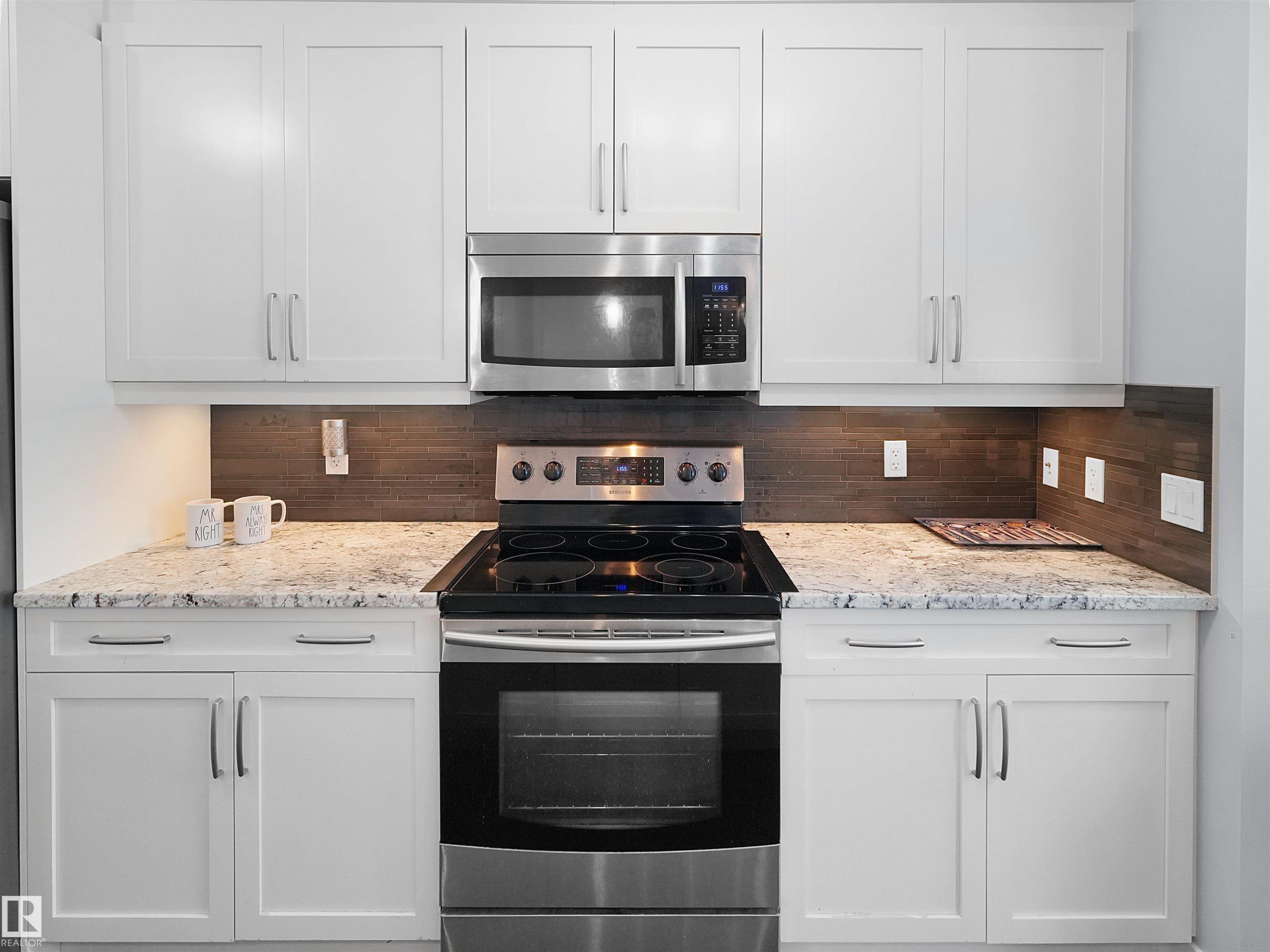White shaker-style cabinetry, stainless steel appliances, speckled stone countertops, and a wood-finish tile backsplash - 6656 Cardinal Rd Sw, Edmonton, AB