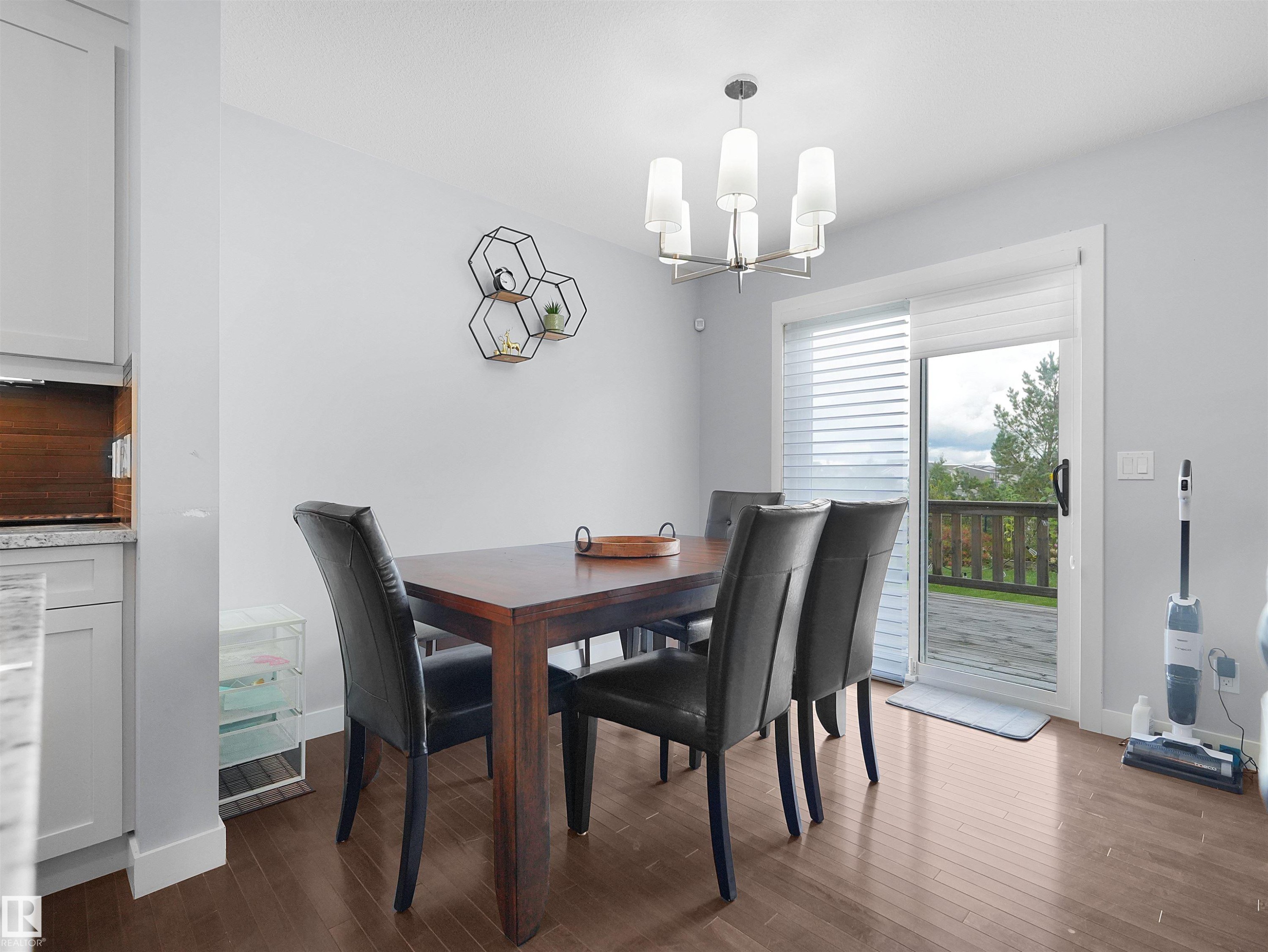 Hardwood-finish flooring, sliding glass door, and a modern chandelier with a brushed nickel finish - 6656 Cardinal Rd Sw, Edmonton, AB