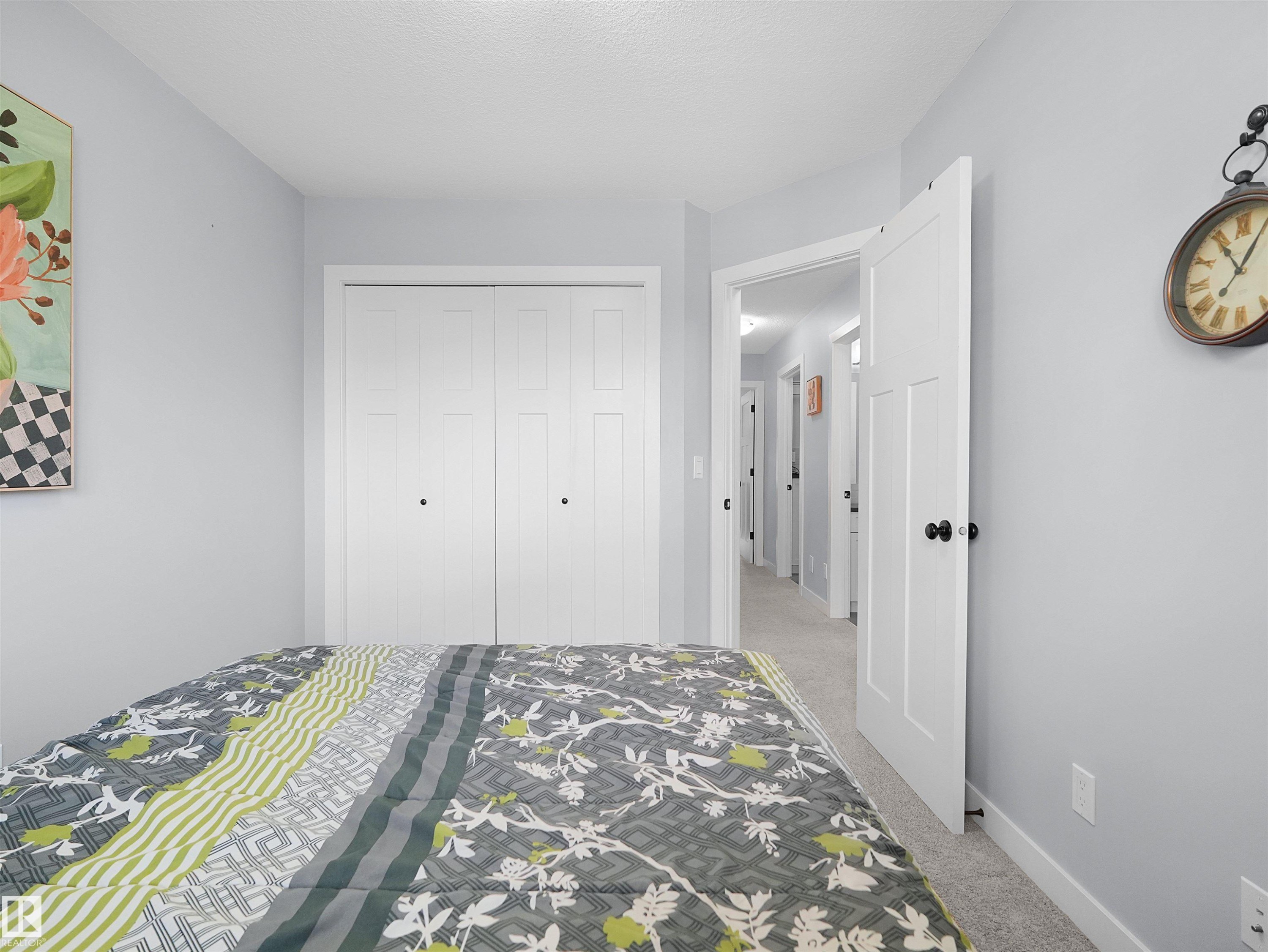 Textured gray carpeting, light blue wall paint, white interior doors, and white bi-fold closet doors - 6656 Cardinal Rd Sw, Edmonton, AB
